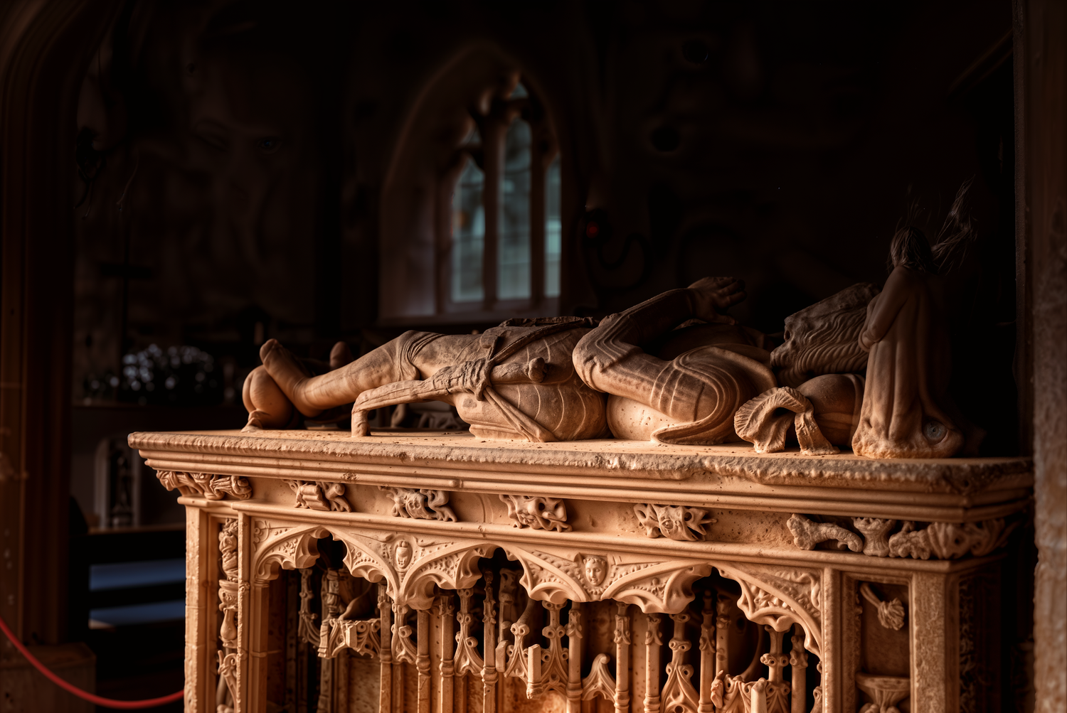 Medieval stone tomb effigy of a knight in a Gothic church, ornately carved with detailed figures and tracery.