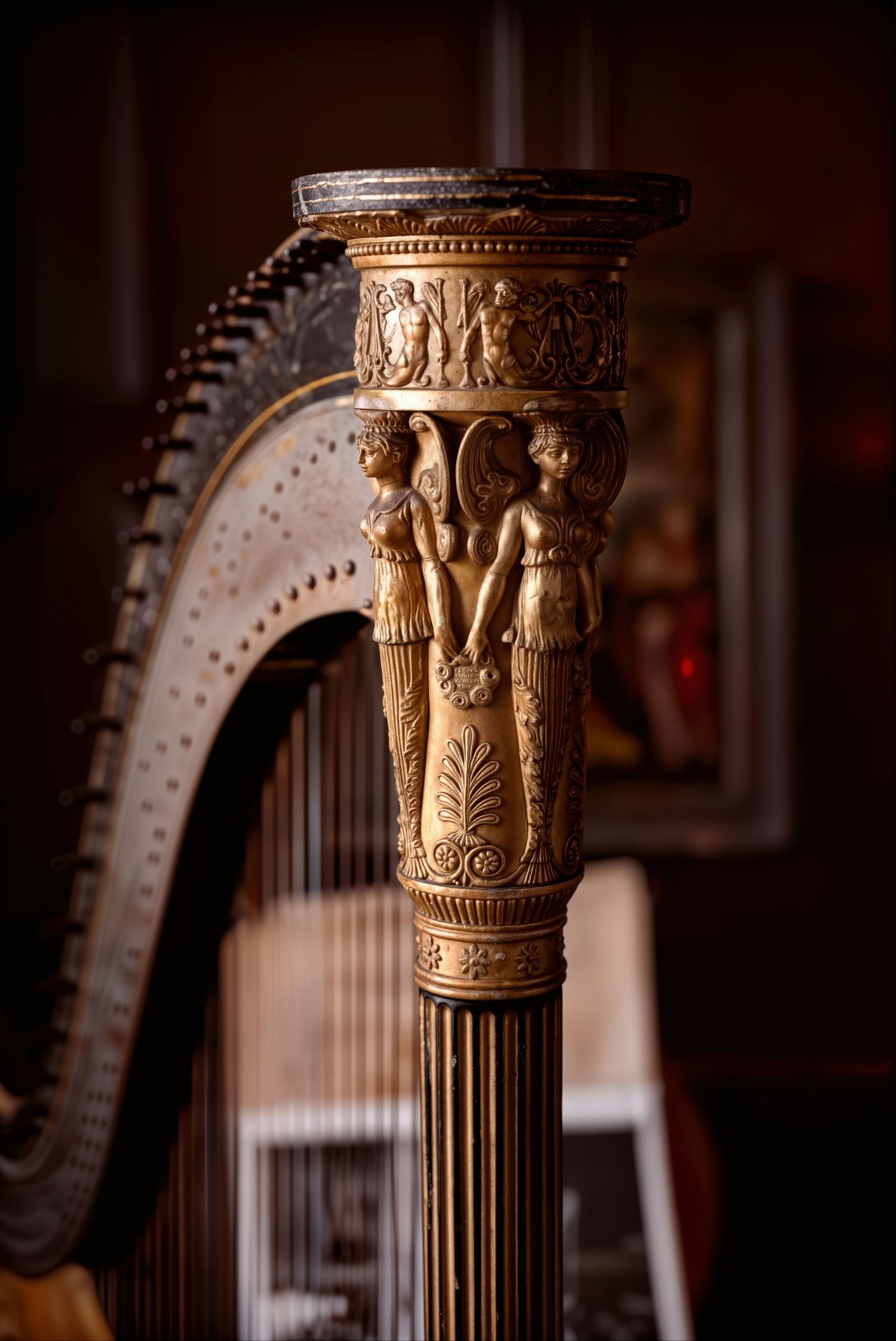 Ornate golden harp column featuring carved classical figures and intricate decorative motifs in an elegant interior setting.