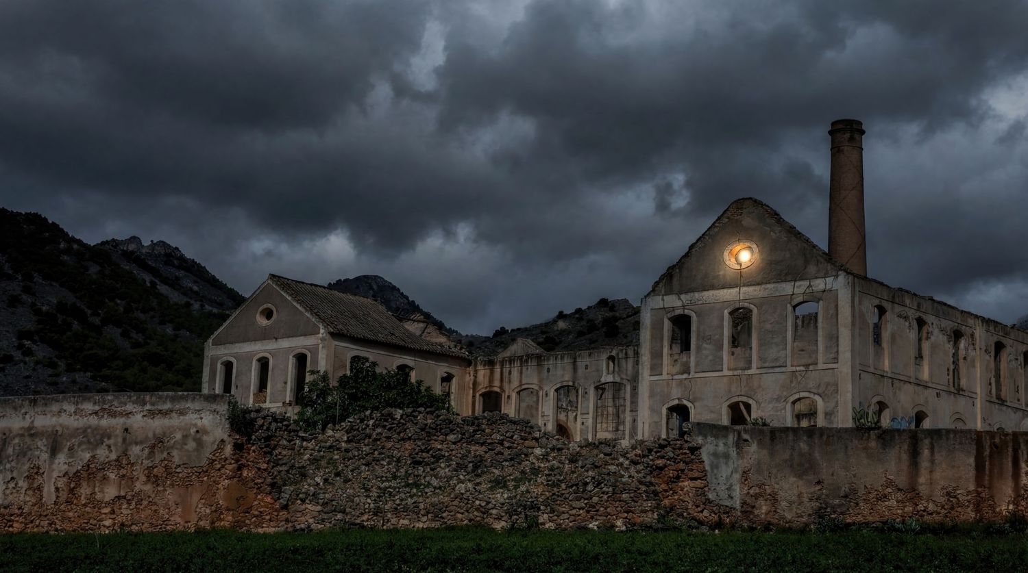 A panoramic view of abandoned stone buildings under dark stormy clouds with dramatic moody lighting.