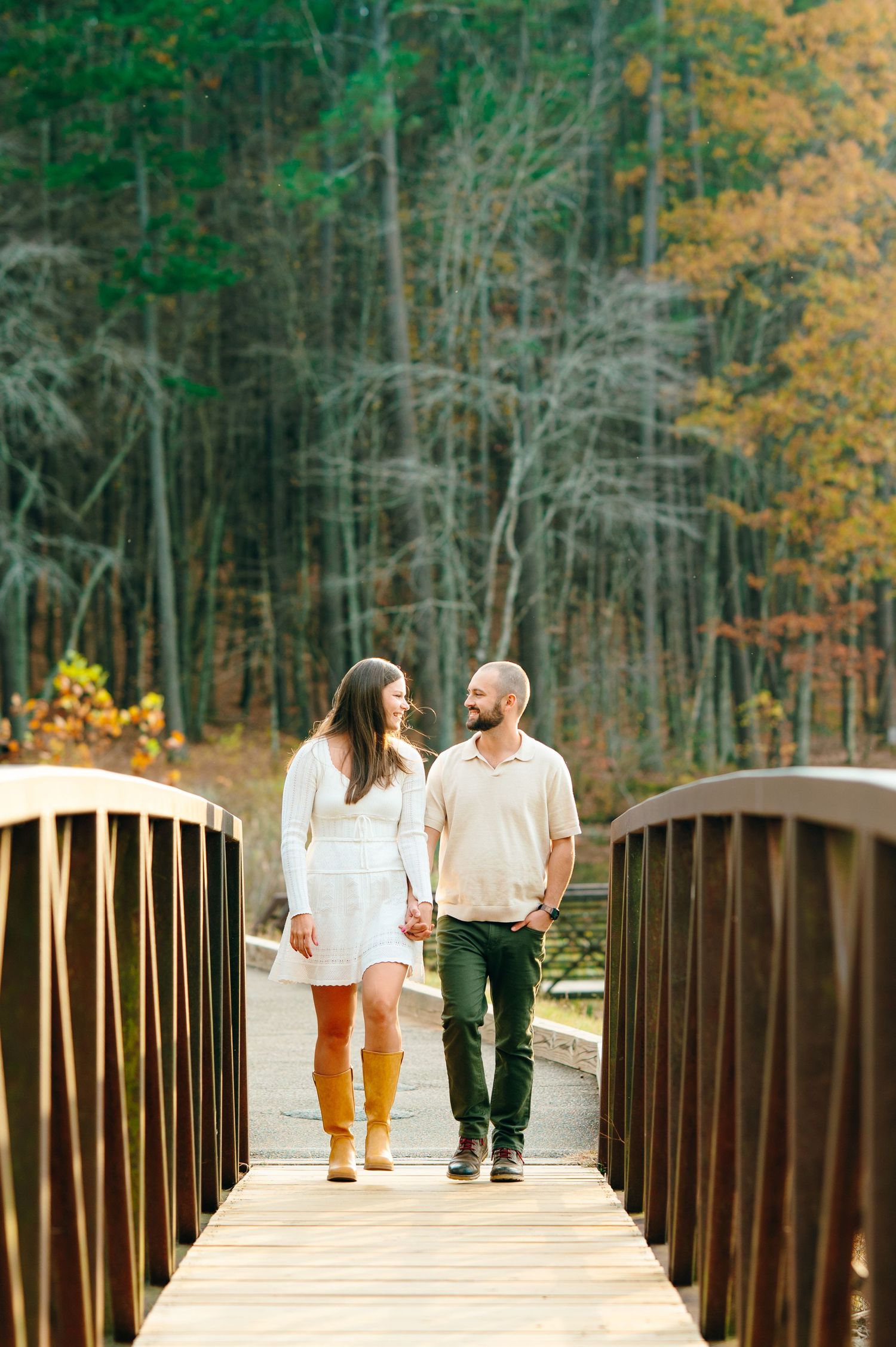 Couples photography walking on bridge in woods in Umstead State Park in Raleigh NC