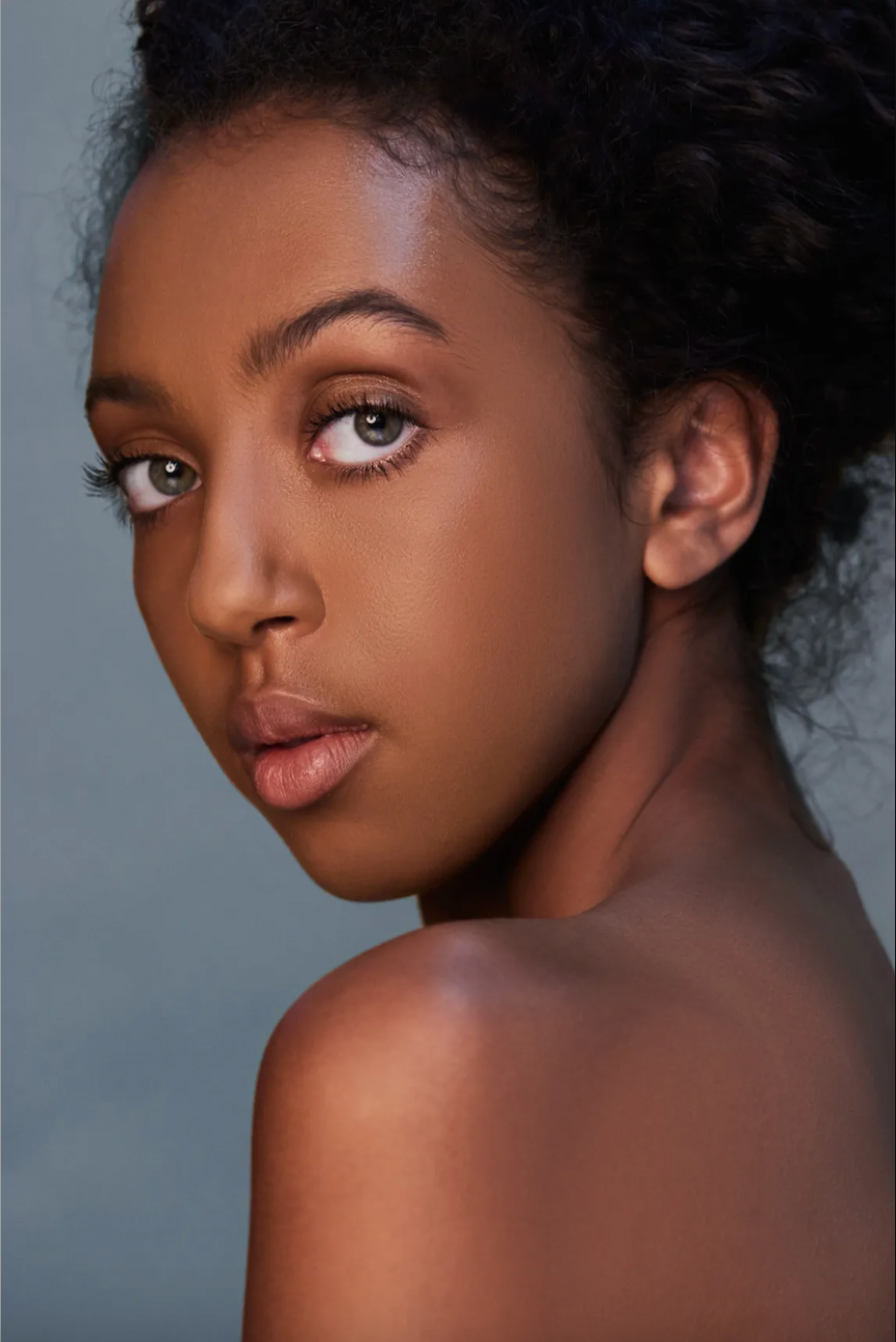 Natural beauty portraits featuring curly hair and glowing skin against dark gray backdrop.