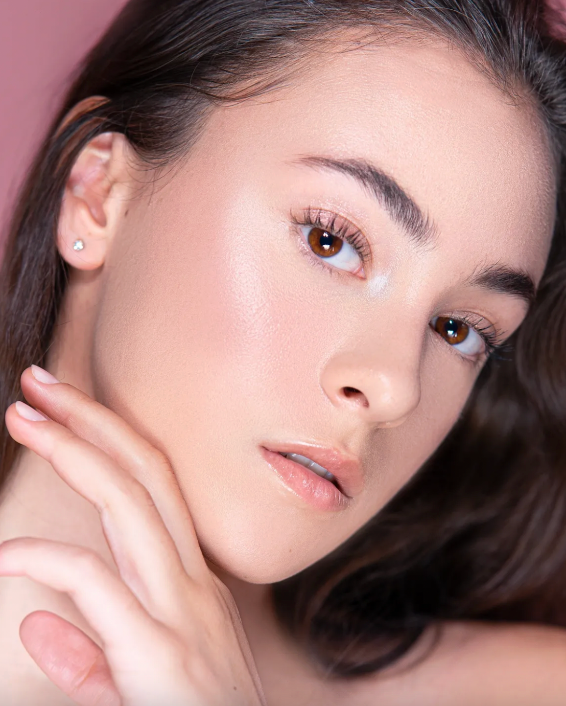 Soft beauty closeups showing natural makeup and dark hair against pink background.