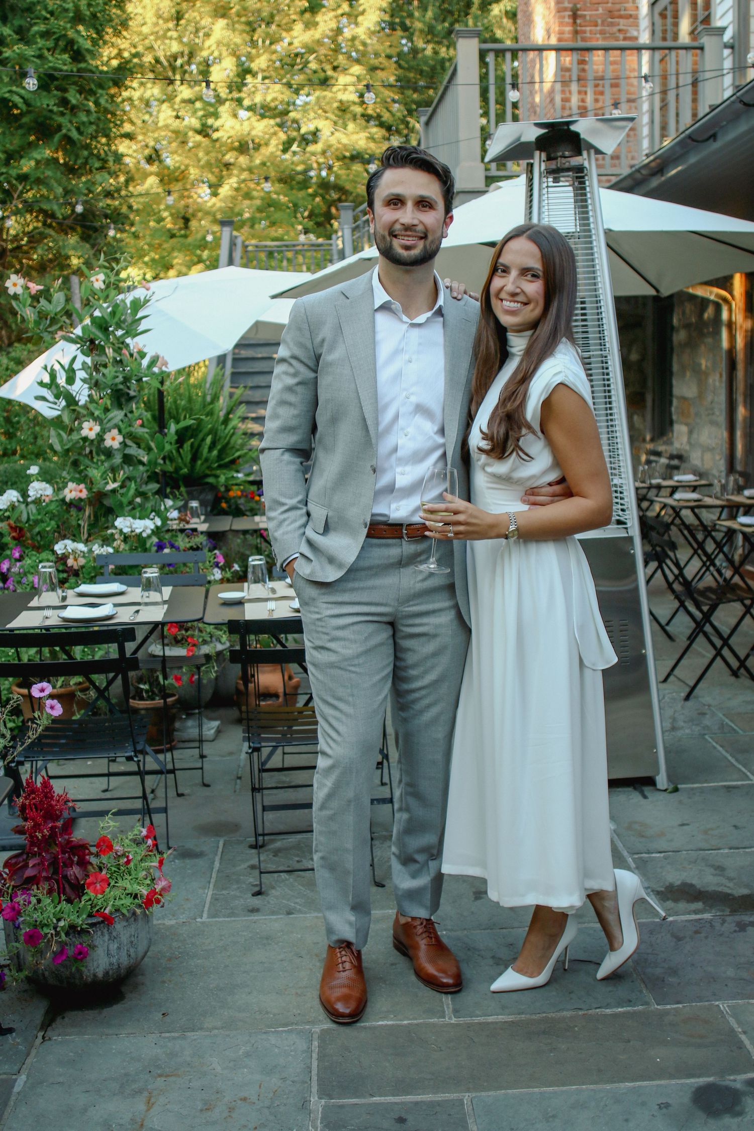 Elegant couple posing together smiling at outdoor garden restaurant patio.
