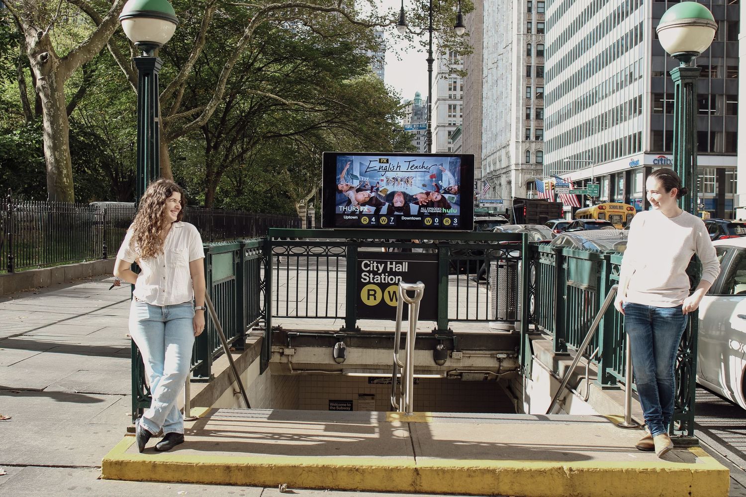 Two women standing at a City Hall subway station entrance in New York City on a sunny day.