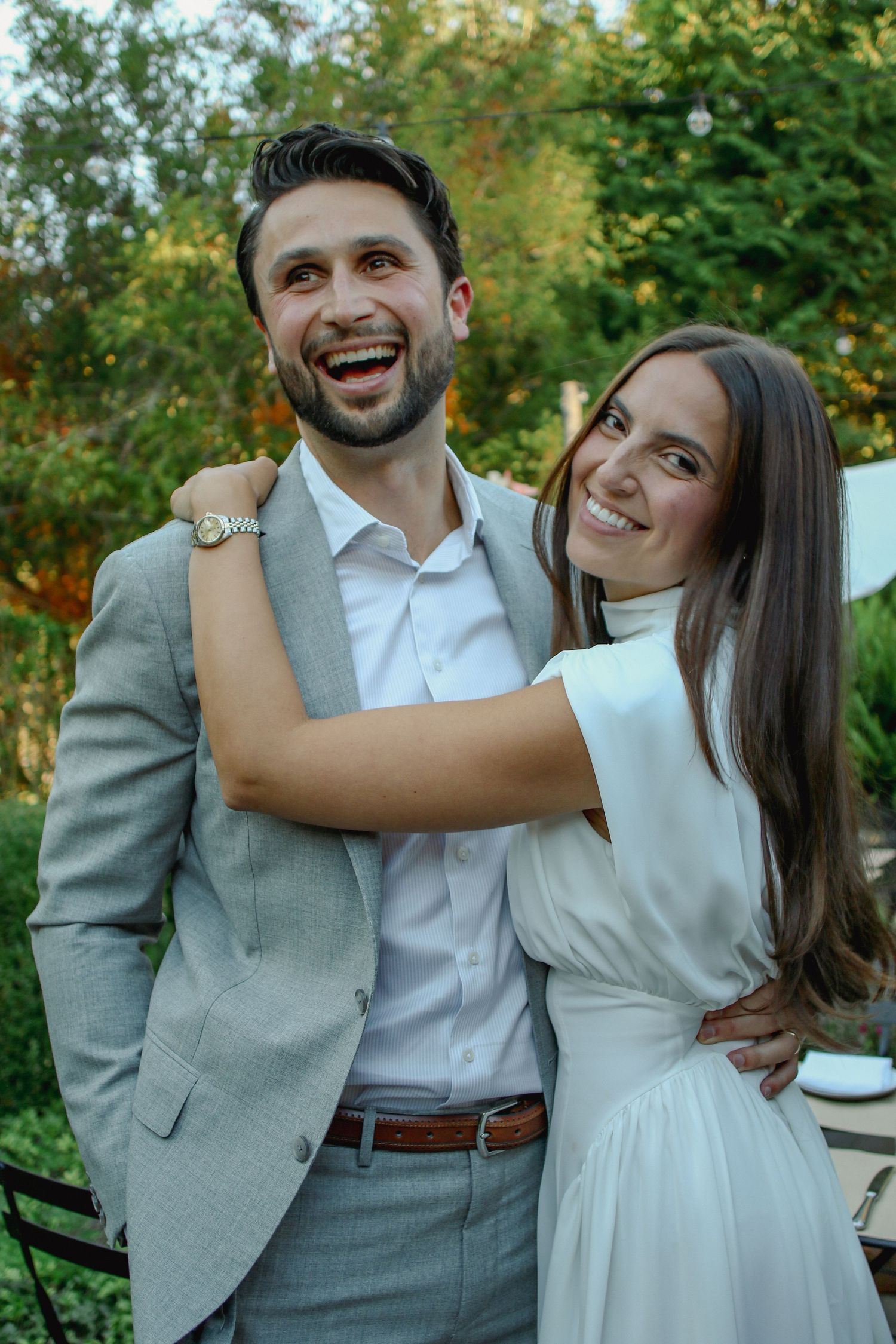 Happy couple embracing and smiling together in lush garden setting.