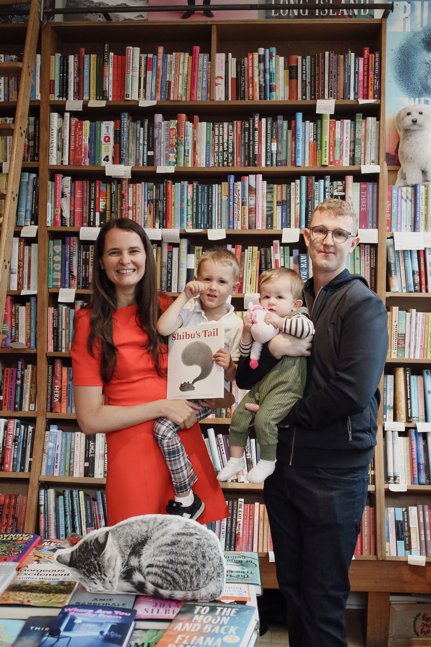Family posing with a book in a cozy bookstore filled with colorful shelves.