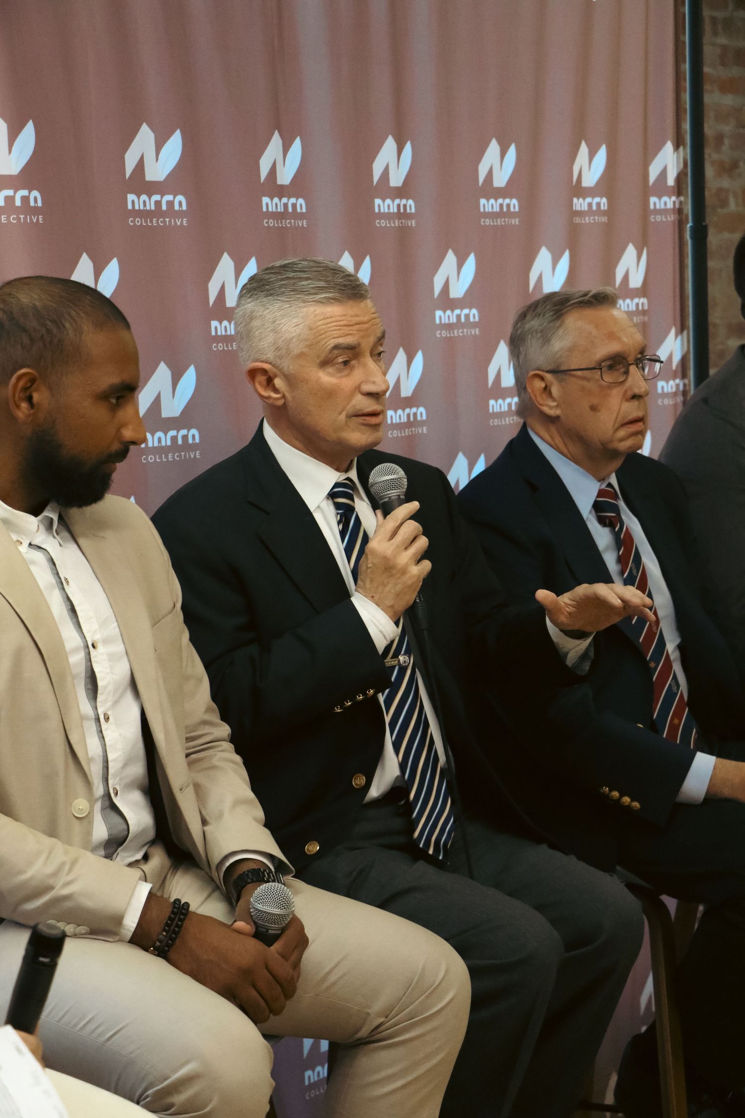 Three men seated at Narra Collective panel, center man speaking into microphone.