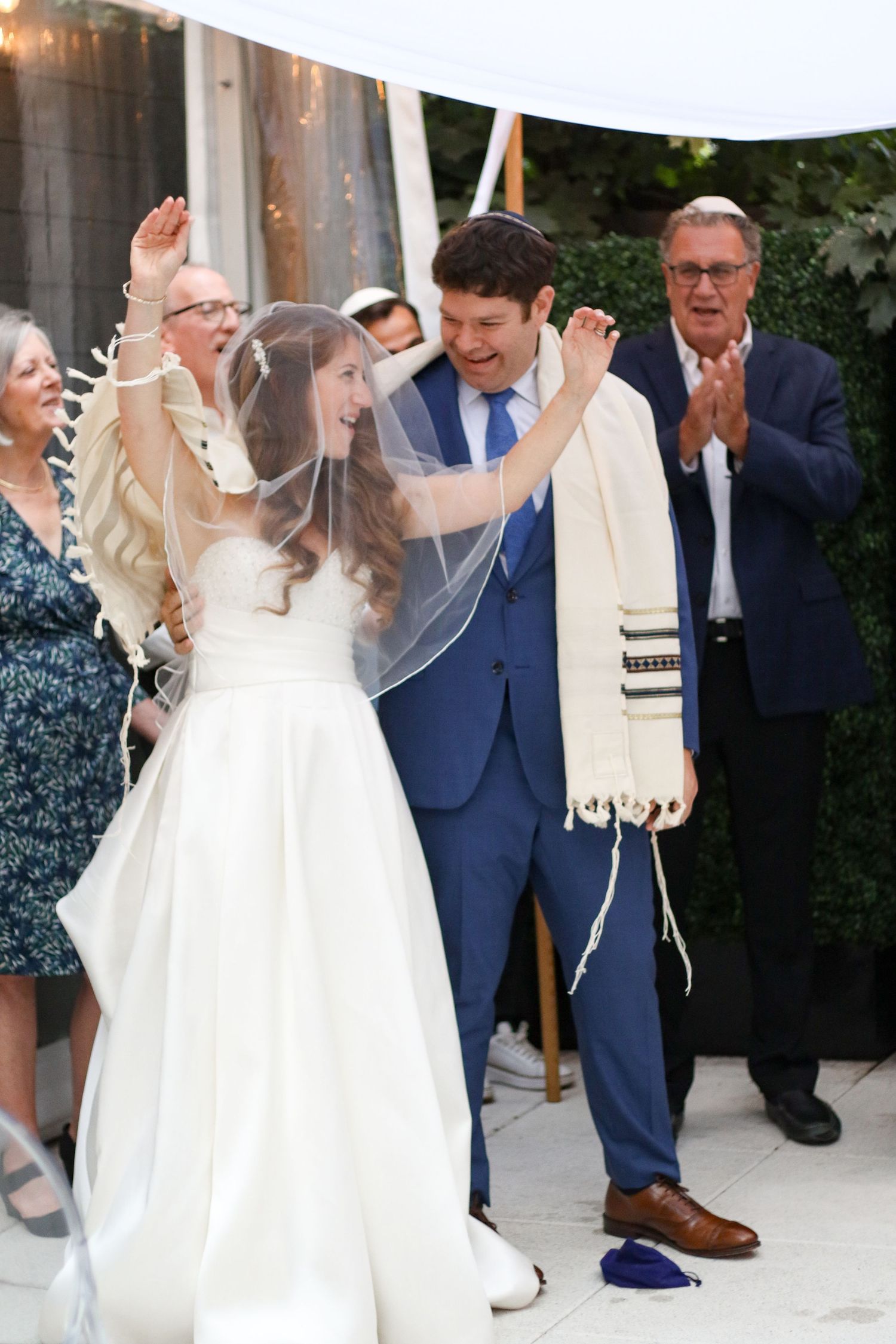 Joyful Jewish newlyweds celebrate with raised hands after breaking the glass at their wedding.