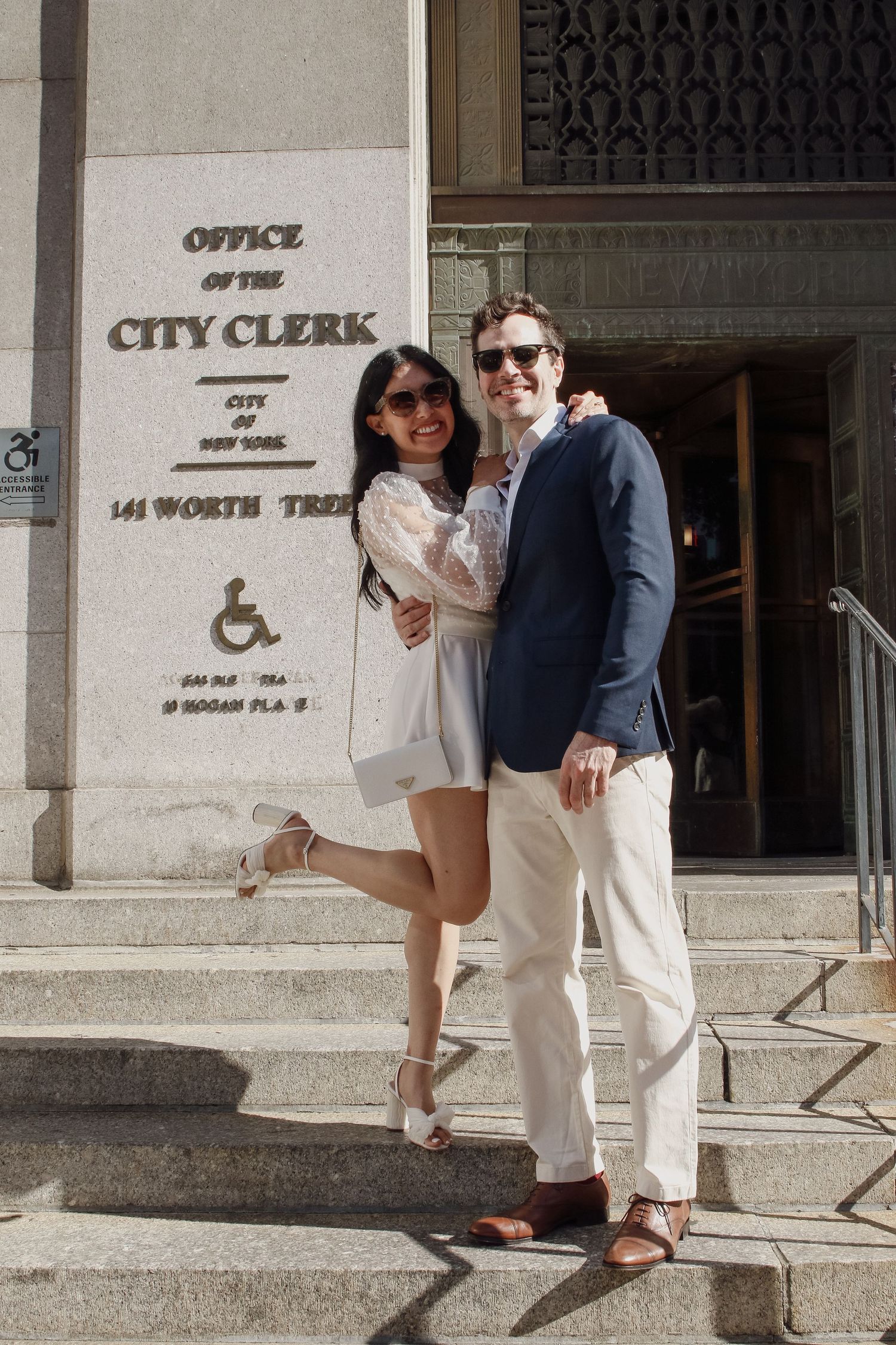Happy couple poses on steps of NYC Office of the City Clerk at 141 Worth Street after their courthouse wedding.