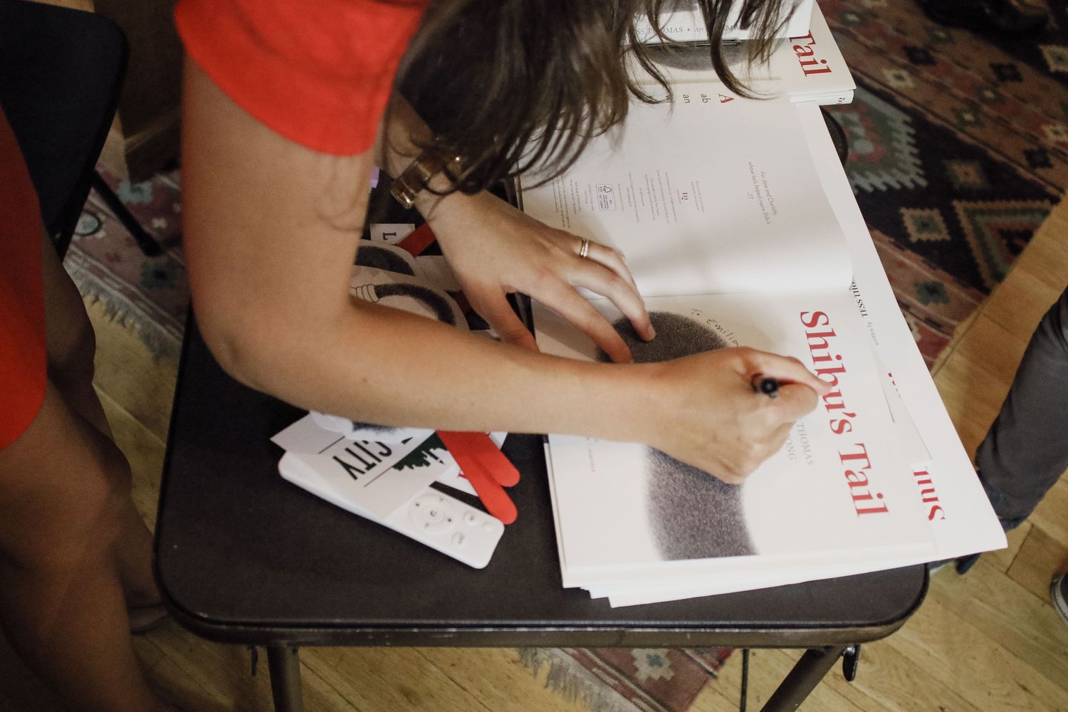 Author signing copies of Shiba's Tail book at a signing event.