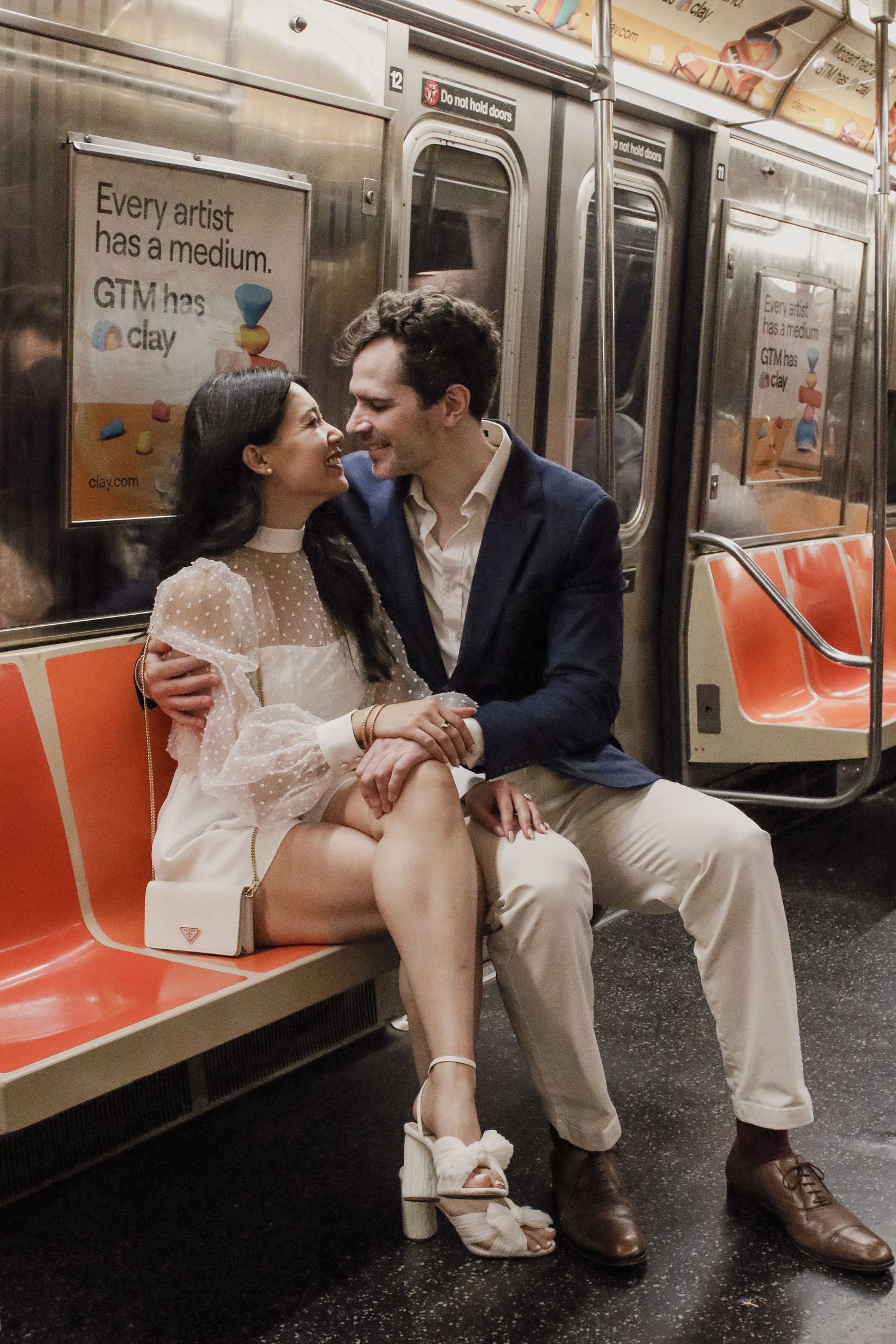 Romantic couple sitting close together and smiling on a New York City subway train.