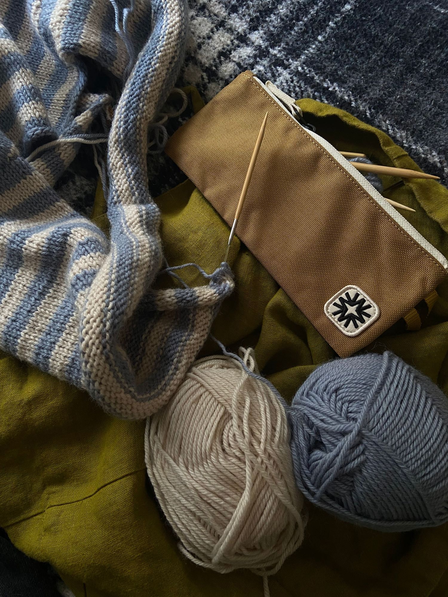 knitting supplies on a blanket with in process blue and white striped sweater