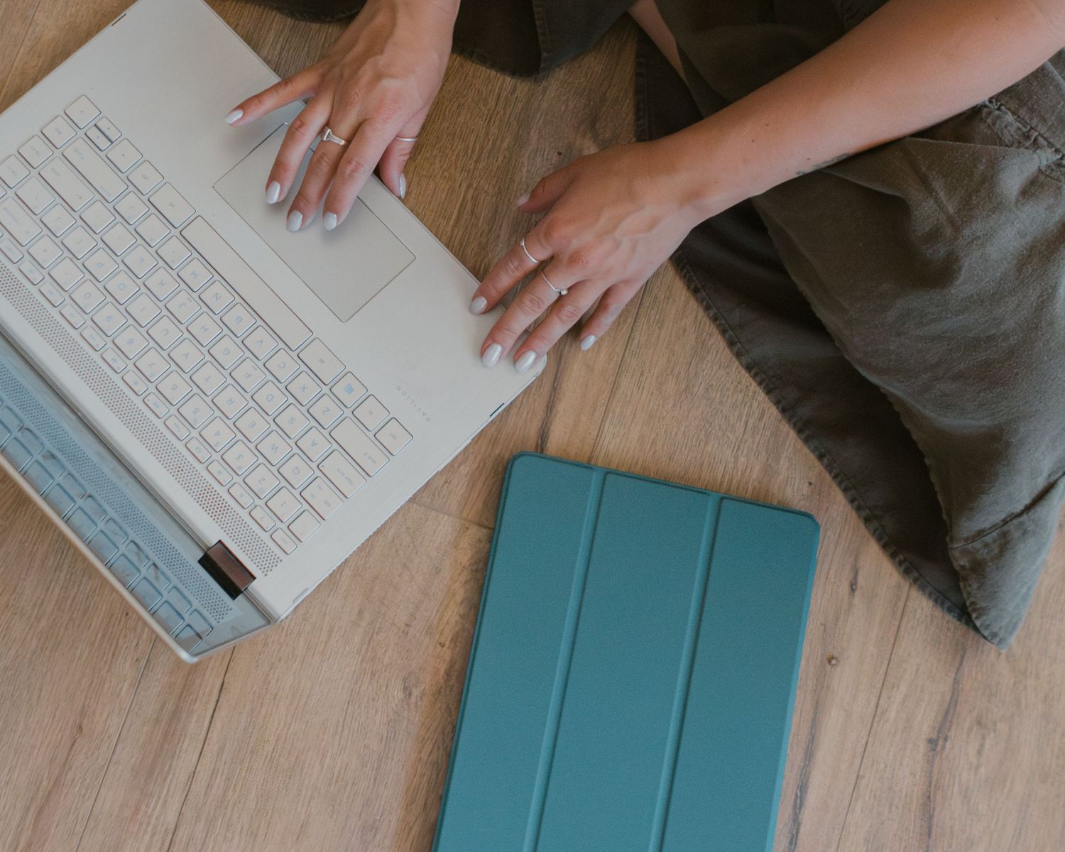 overhead view of someone typing on computer with ipad near by