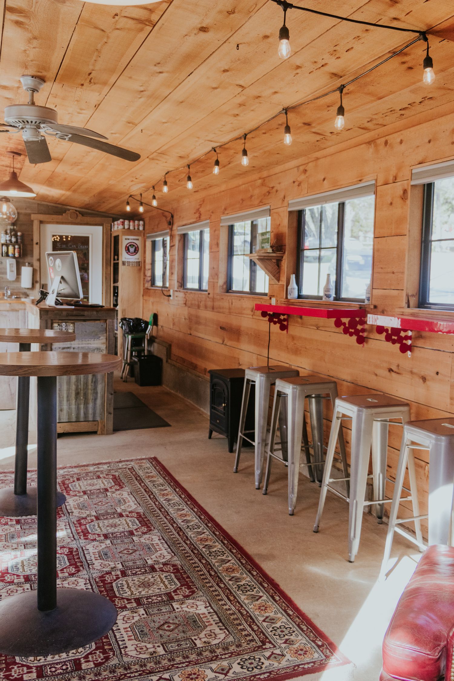 colorful and wooden interior of tap room. metal stools lined up by bar top