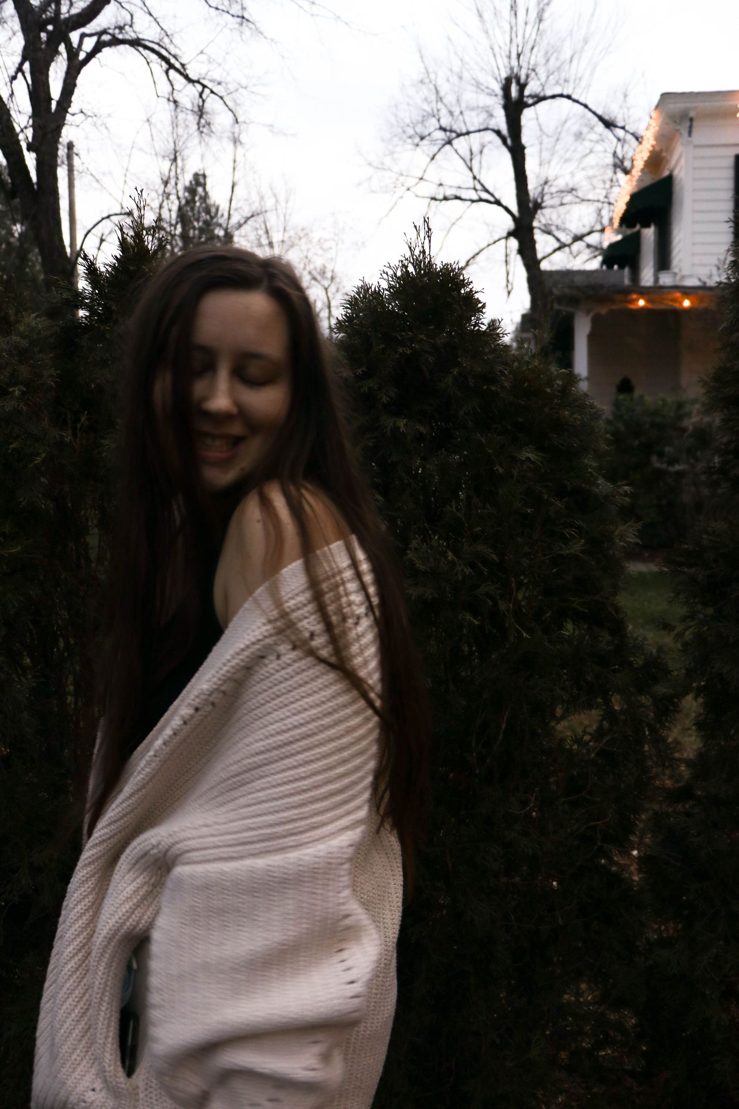 woman wearing white sweater smiles with eyes closed