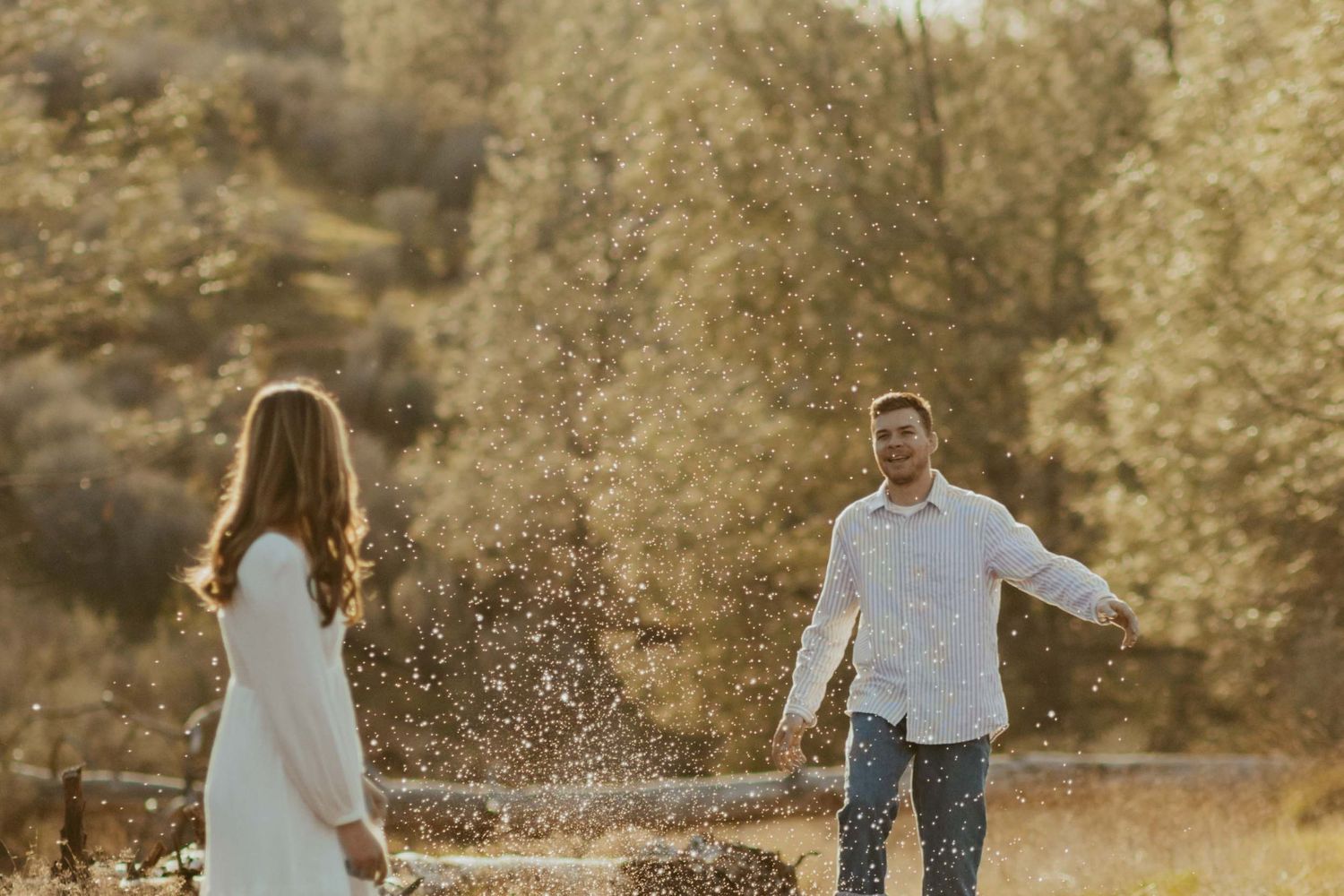 couple stand apart in a river, man kicks water towards woman