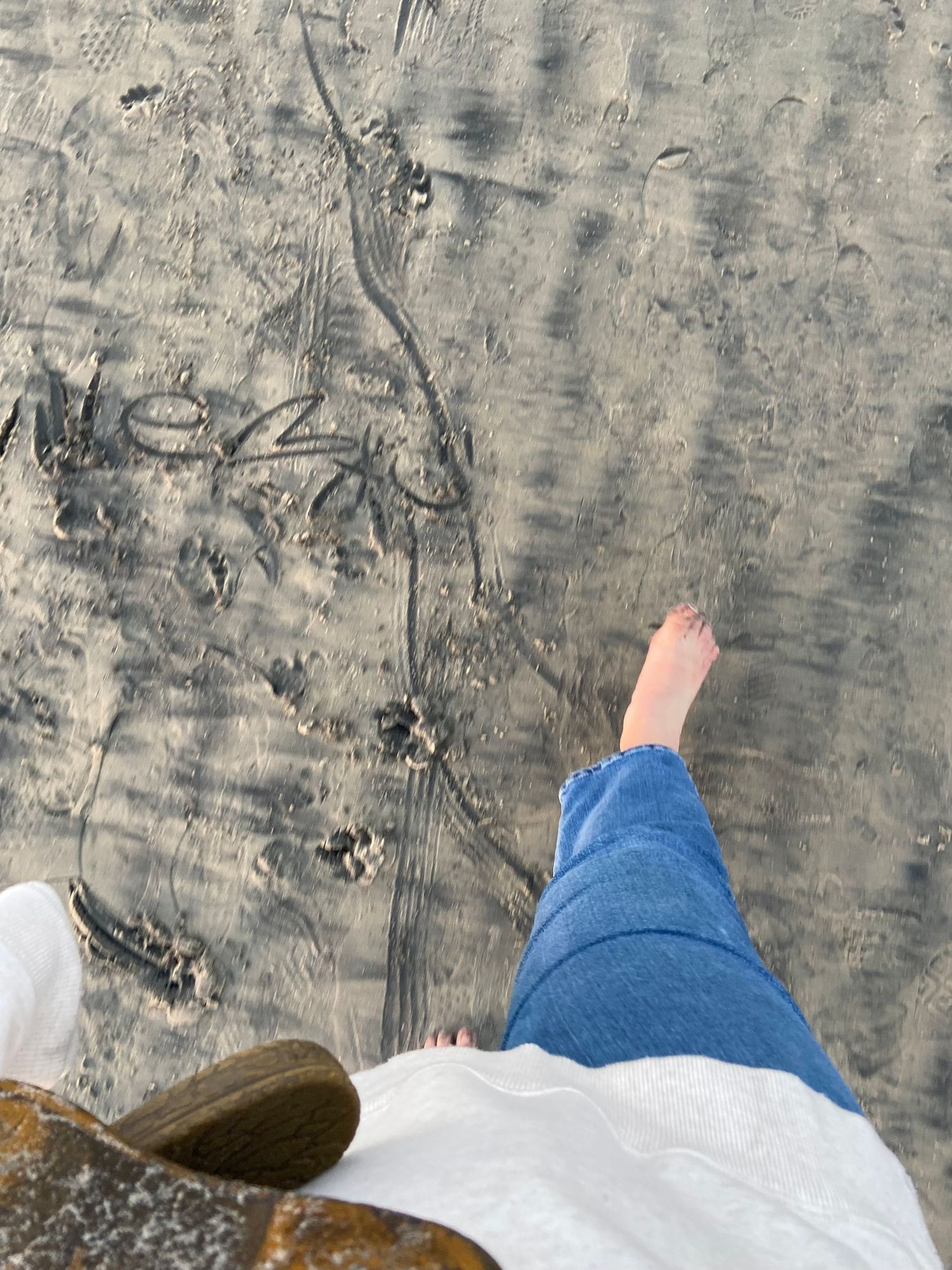 female carrying sandals walking on sandy beach