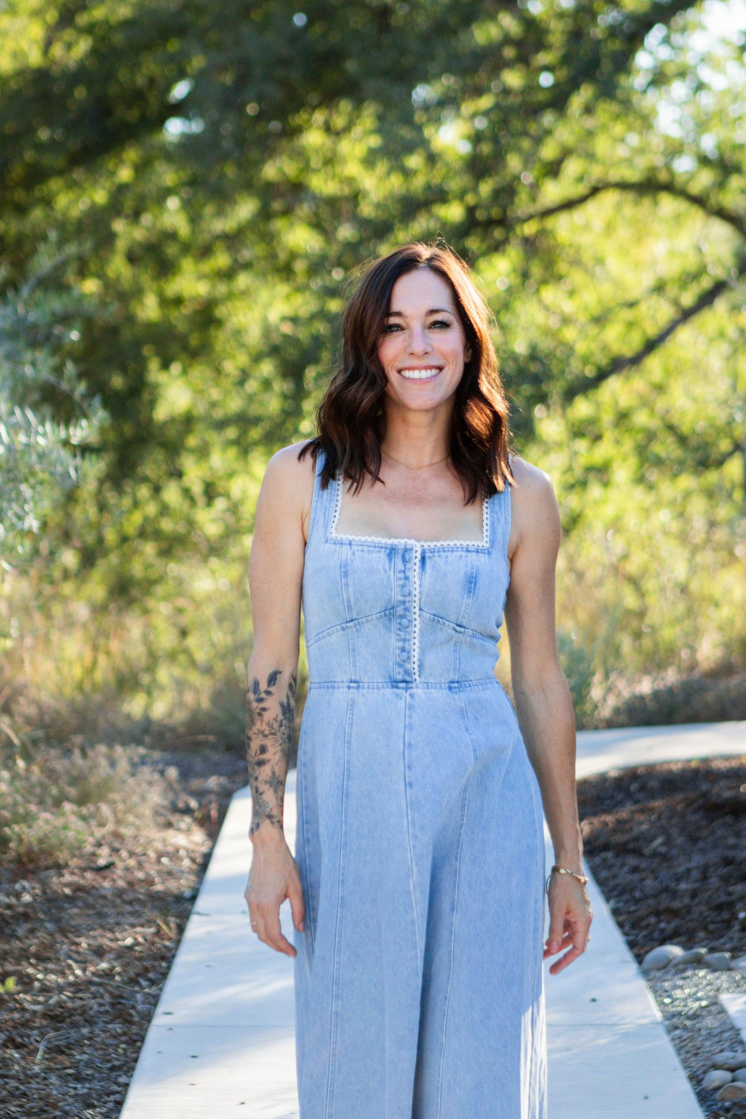 Woman in jean dress walks on path