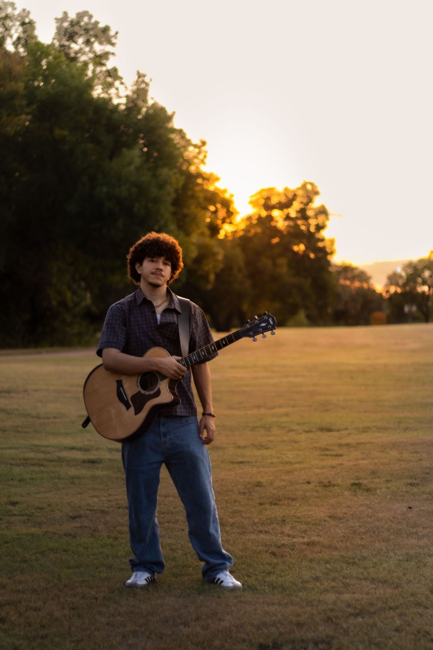 confident high school senior portrait outdoors holding guitar natural light candid smile professional senior photography session musicians