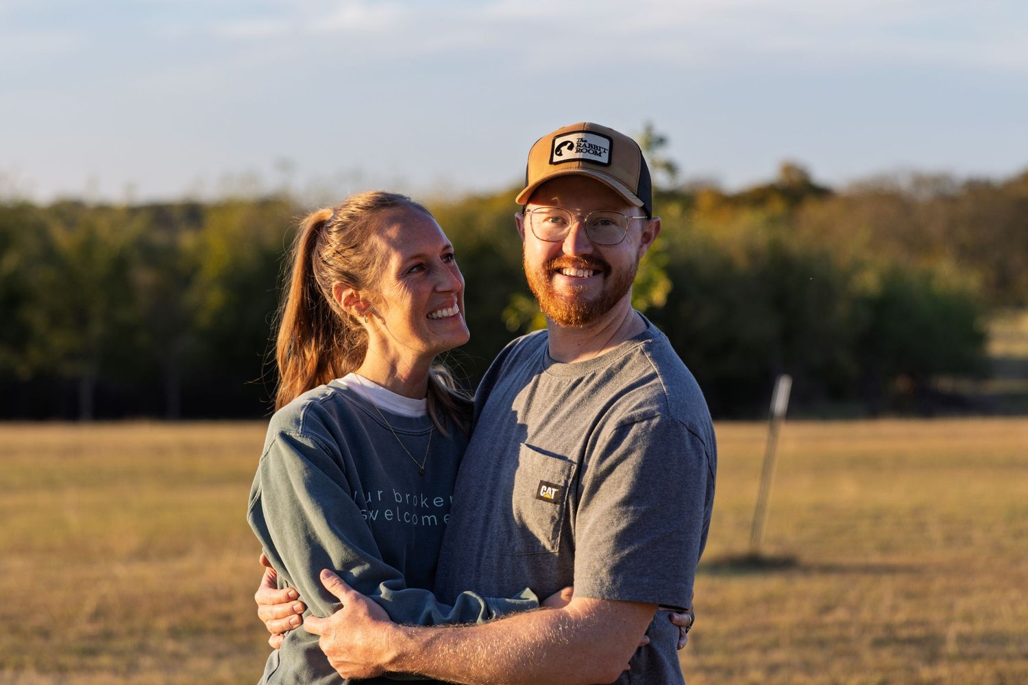 smiling couple embracing outdoors in golden field portrait photography natural light candid moment at sunset