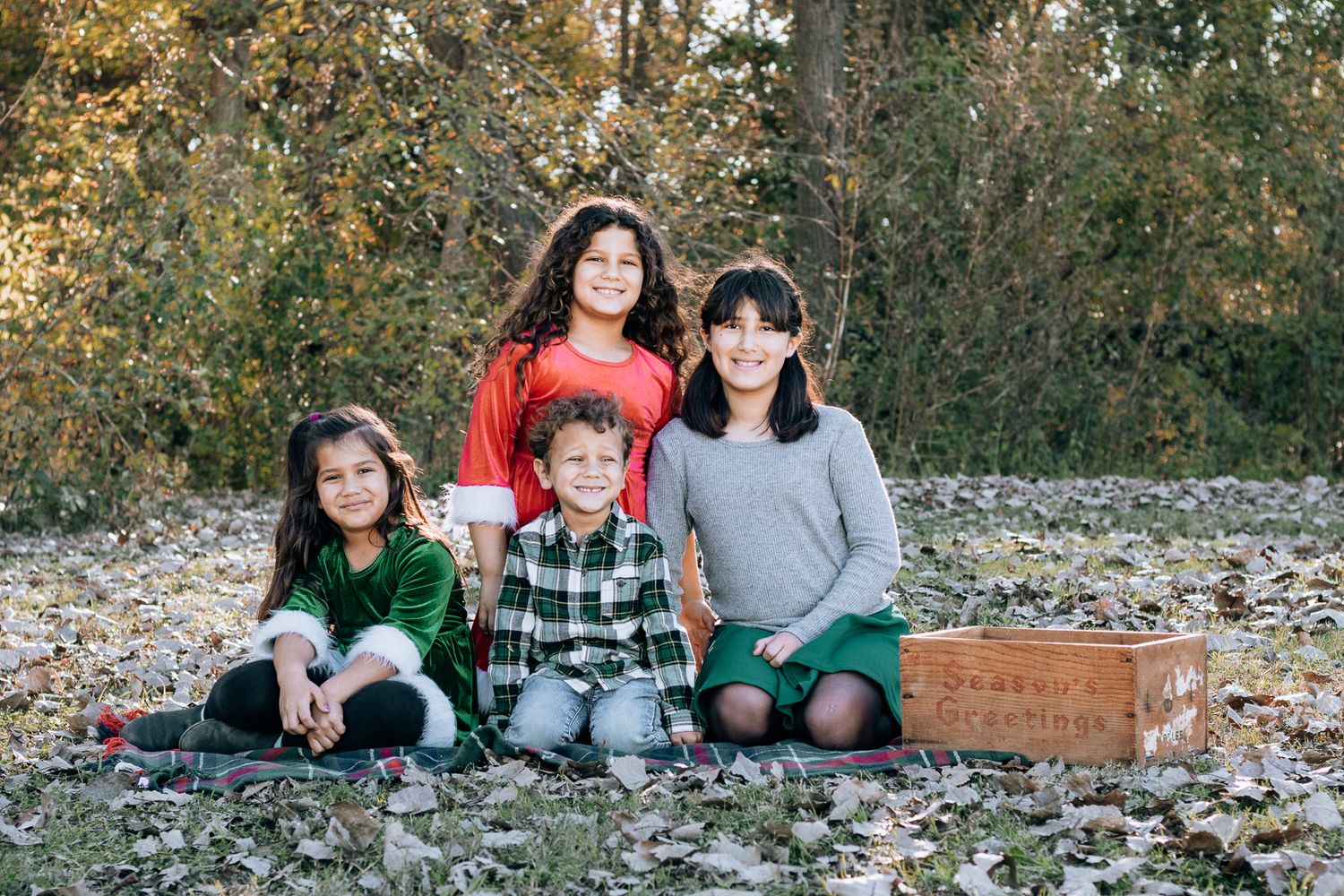 DFW Outdoor family photography session capturing genuine connection and natural expressions sitting on a blanket wearing green and red