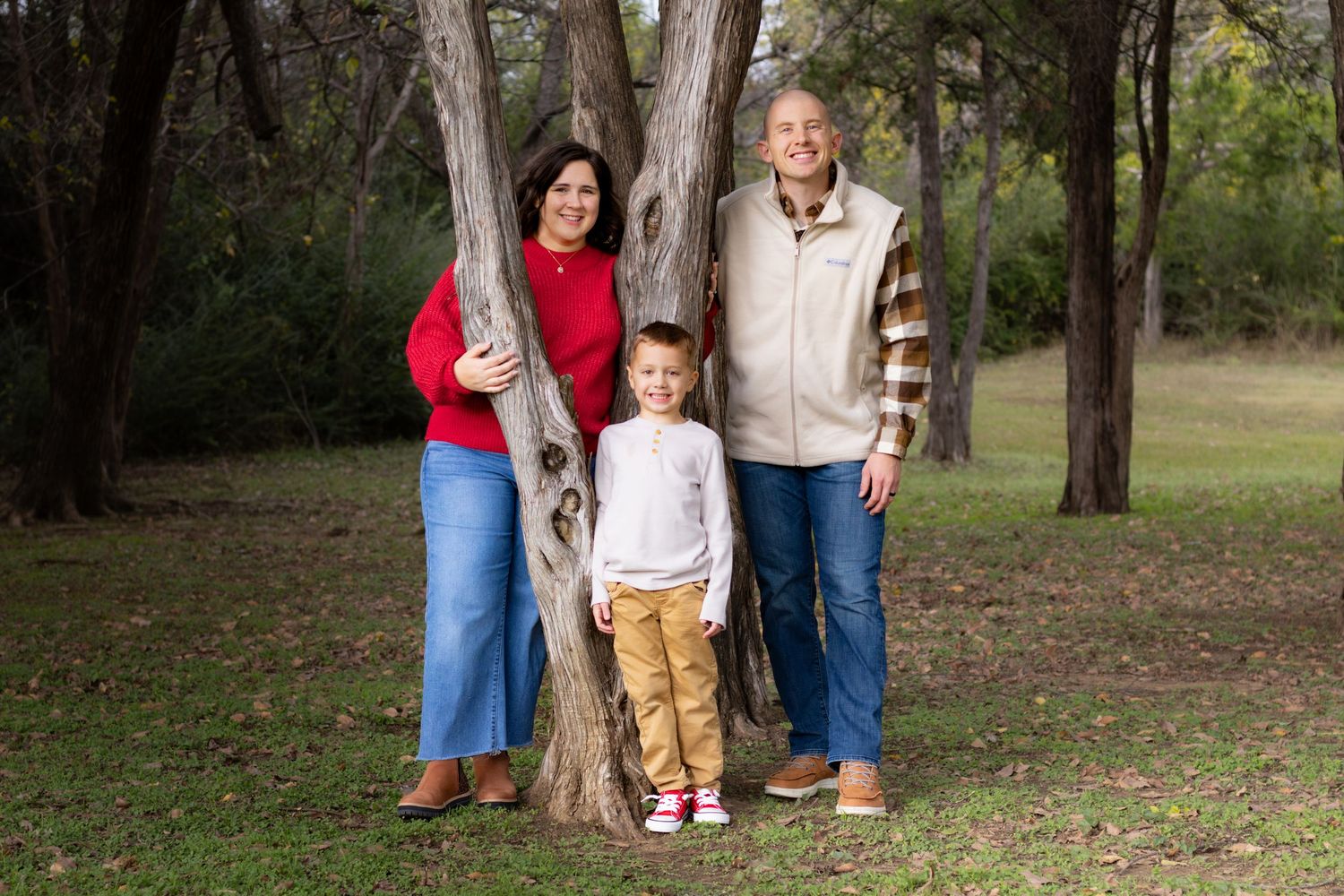 Happy family portrait session outdoors with parents and children, candid connection and warm light smiling and happy natural poses with tree