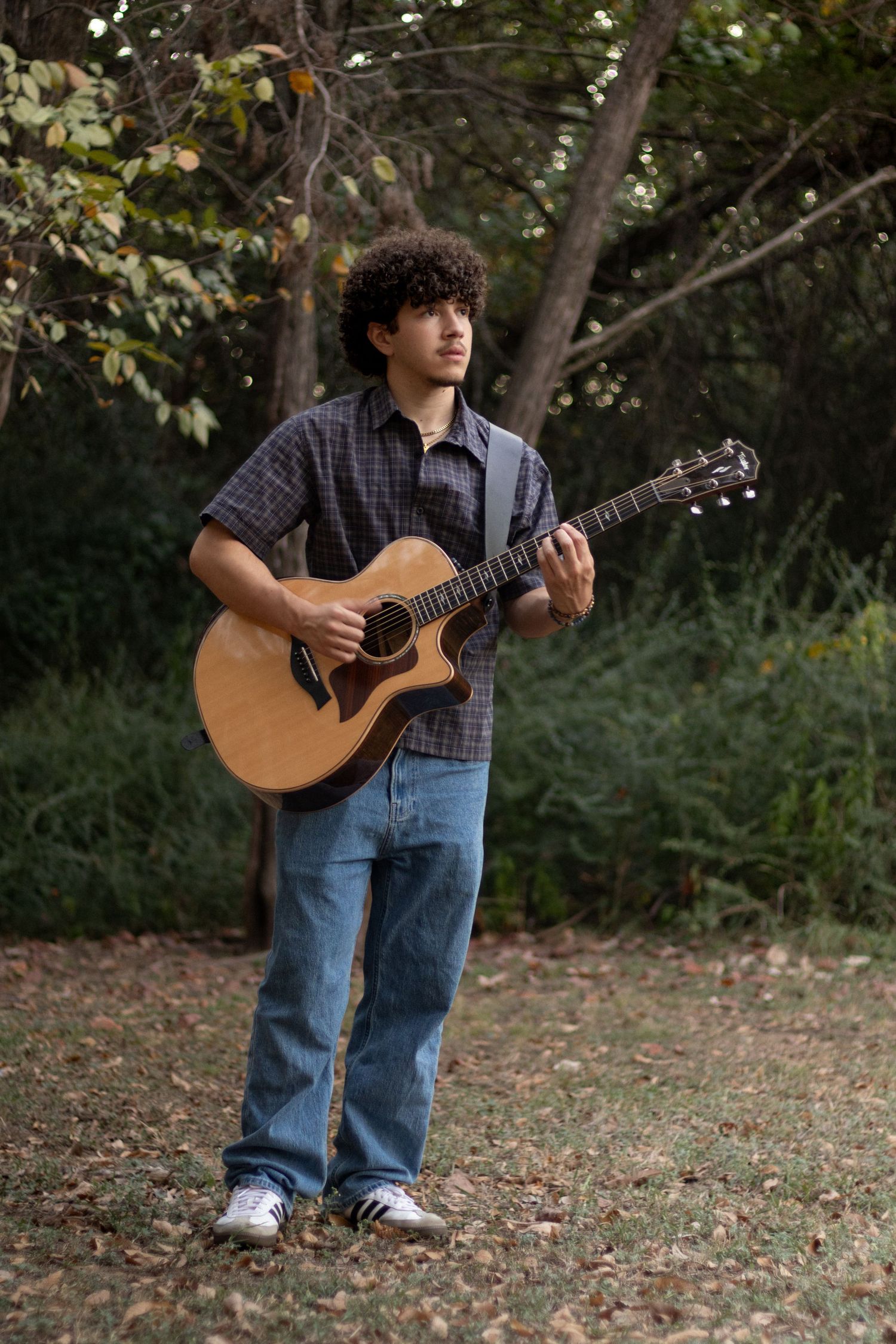 stylish high school senior portrait outdoors smiling confidently in natural light professional senior photography musician playing guitar