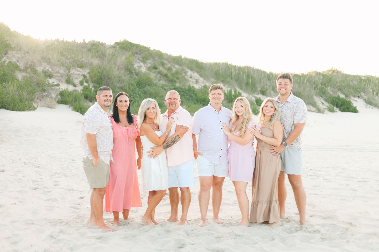 Group photo session on a sunny beach with coordinated pastel outfits.