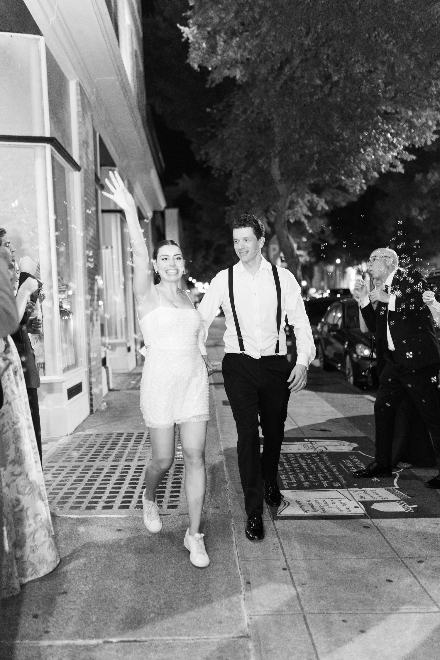Black and white nighttime street scene with people walking.