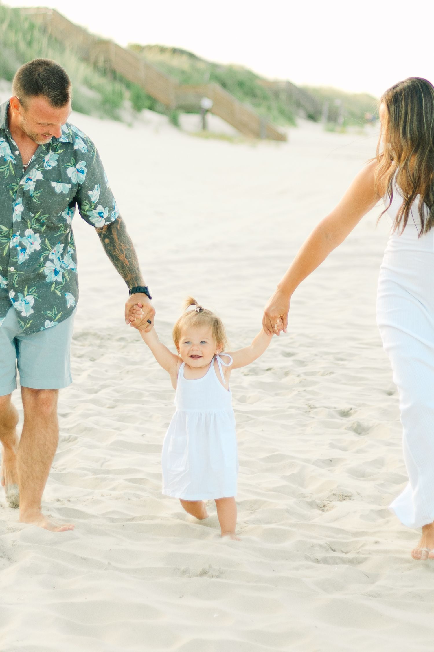 Family holding hands and playing together on a sunny beach.