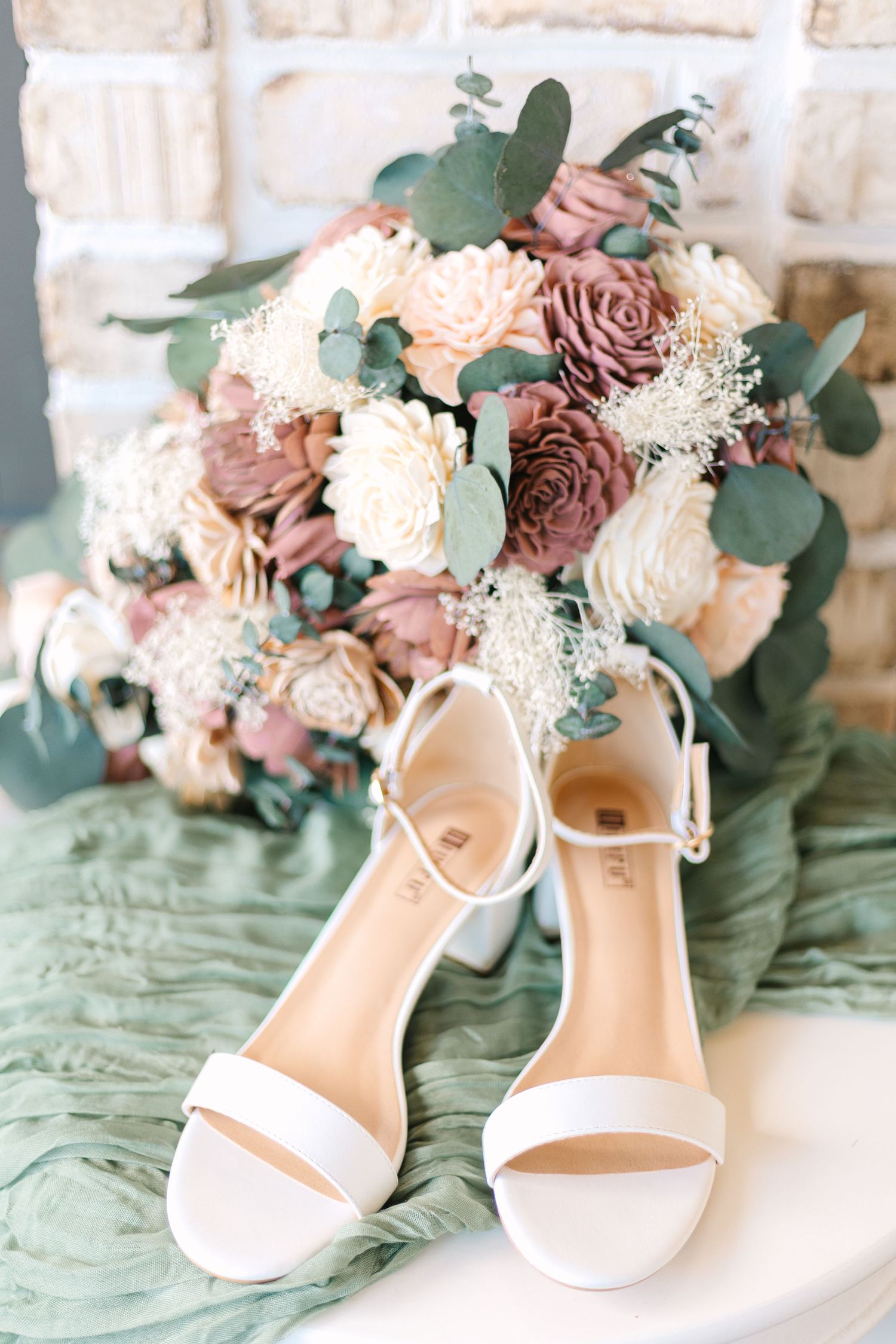 White bridal shoes displayed with a romantic dusty rose and eucalyptus wedding bouquet.