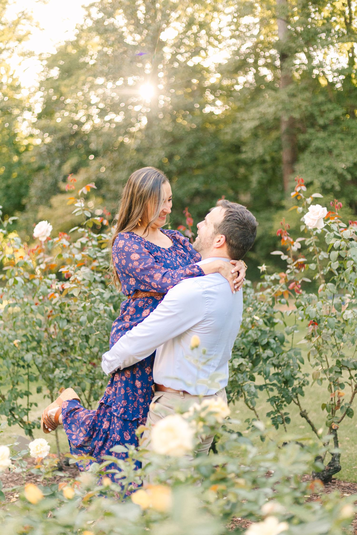 Romantic couple embracing in blooming rose garden during sunset.