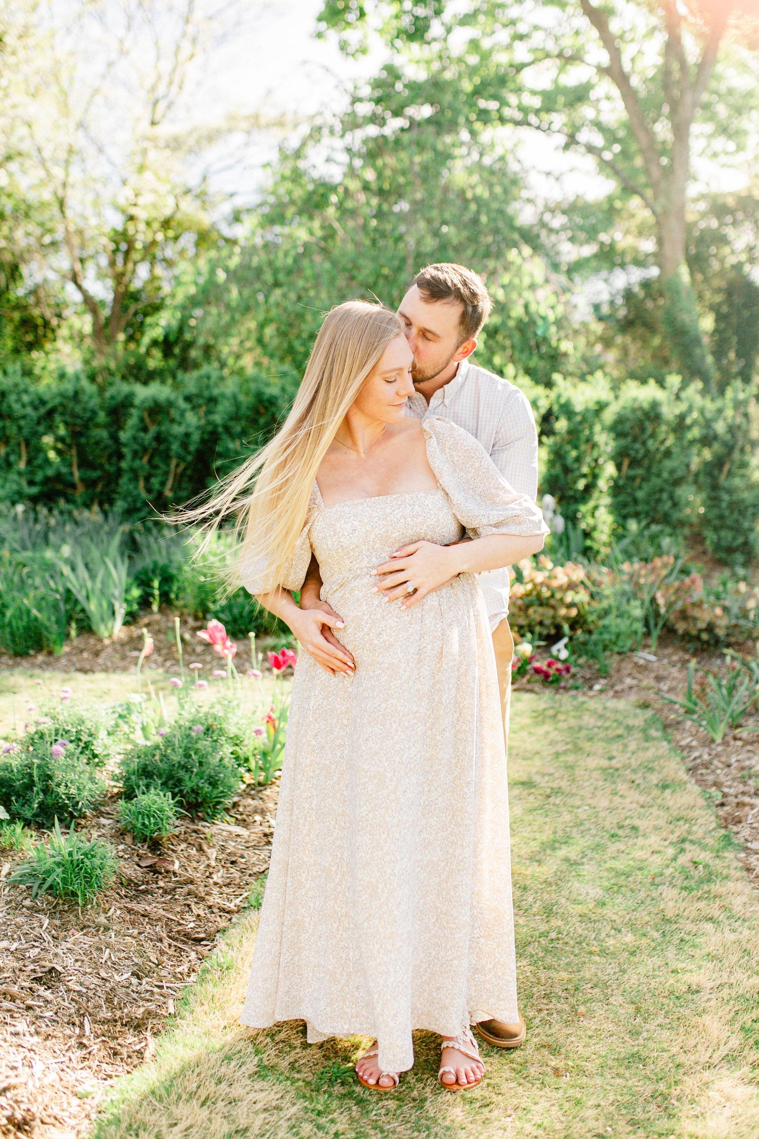 Couple sharing intimate moment in lush garden setting during golden hour.