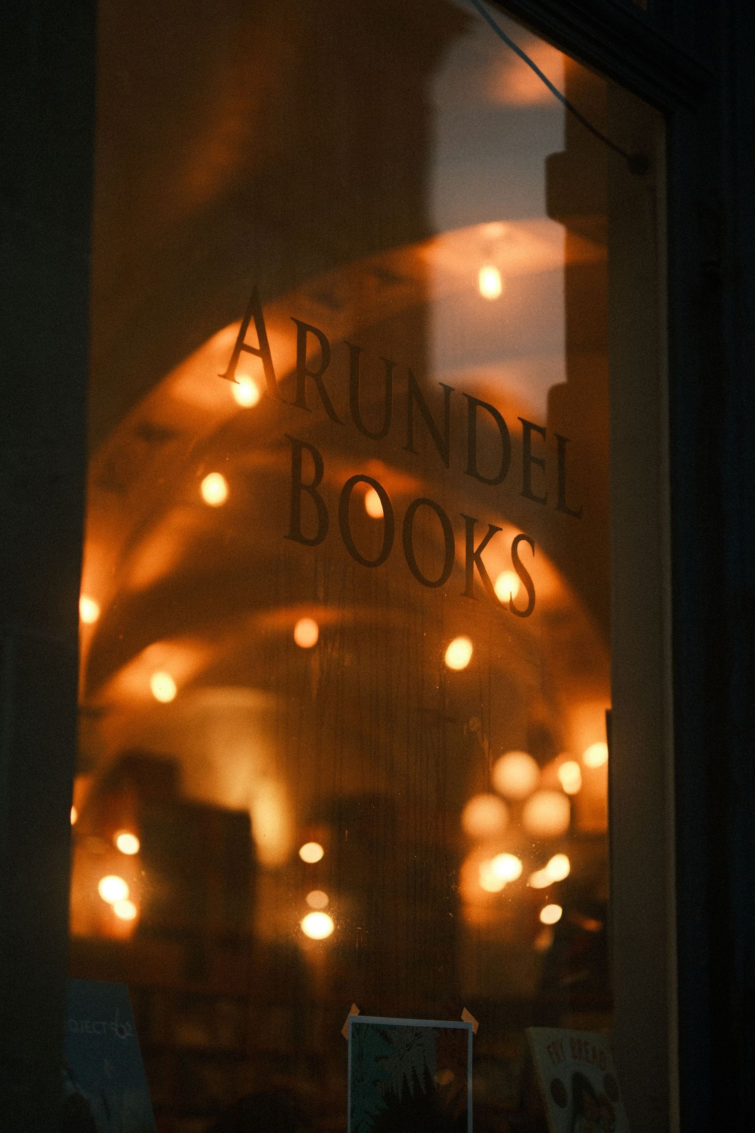 Vintage-style bookstore sign illuminated by warm string lights in darkness.
