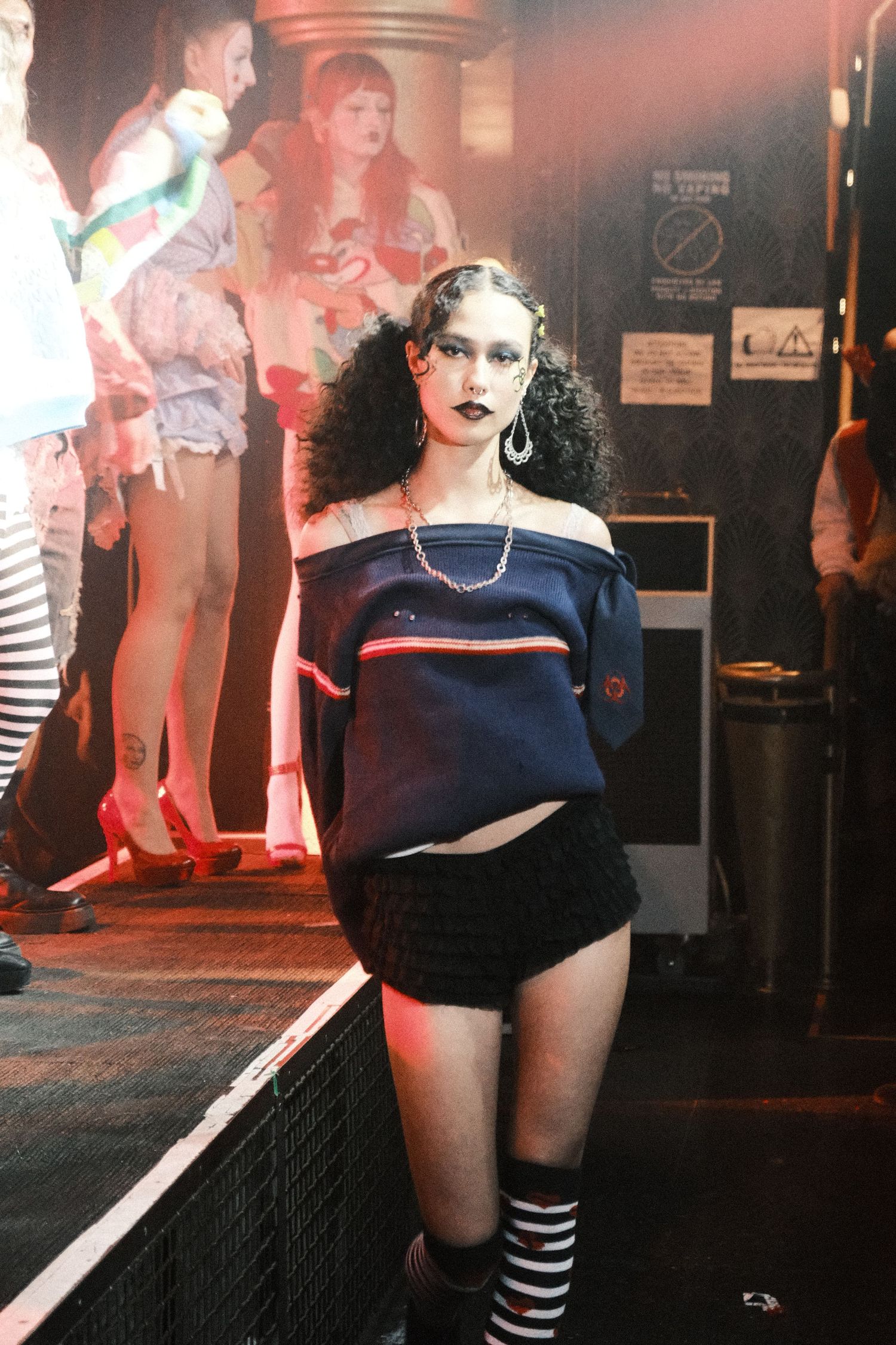 Performance scene with striped socks and dark clothing on stage under red lighting.