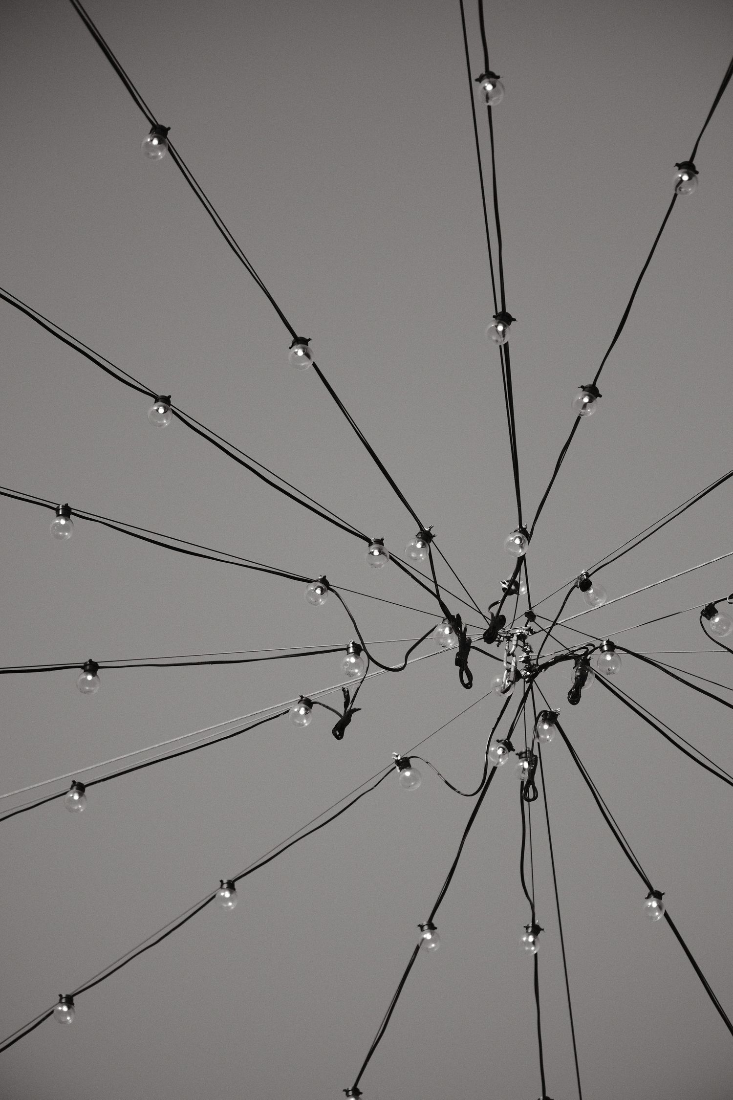 Abstract pattern of interconnected string lights forming a radial design against a minimalist gray background.