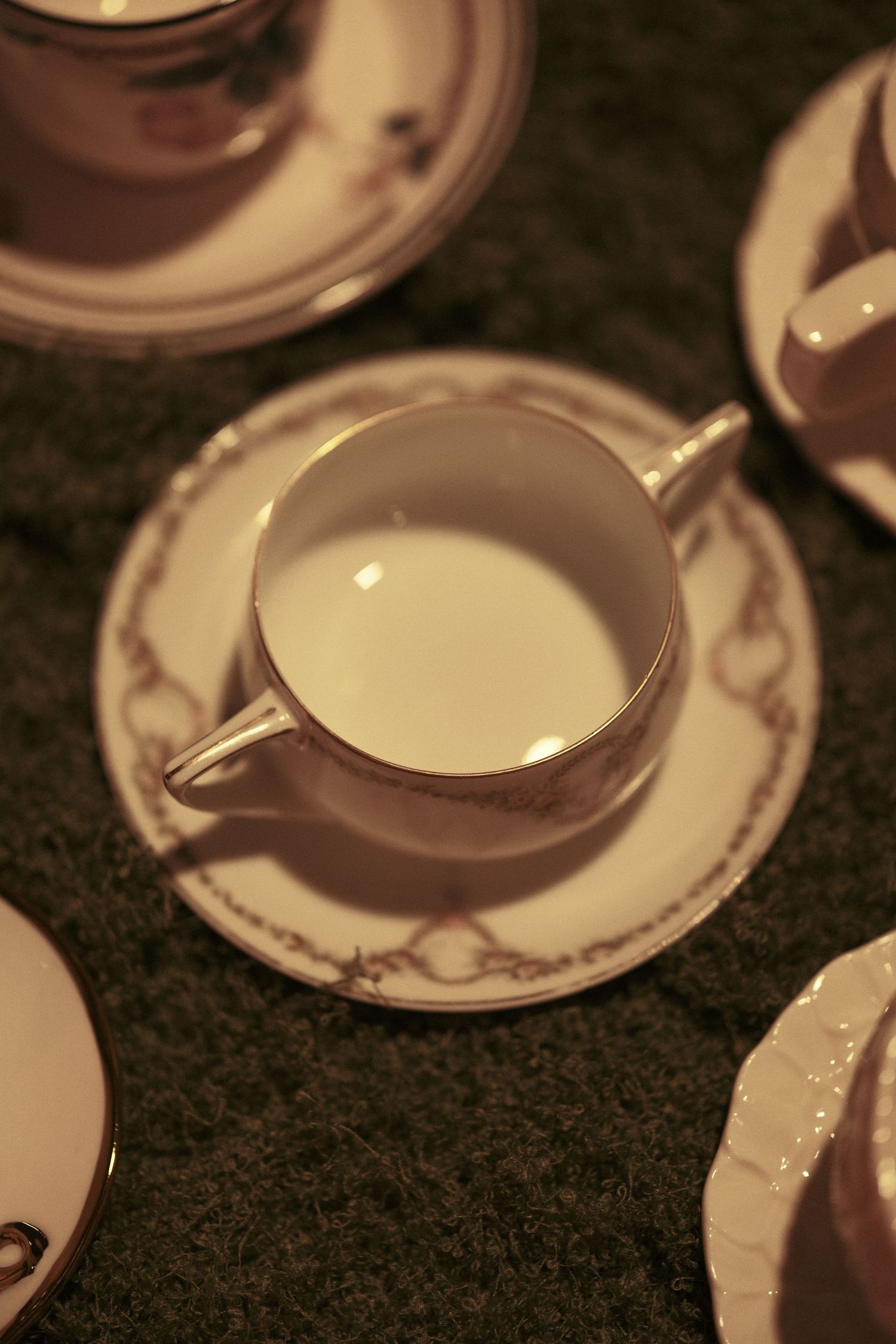 Elegant white porcelain plates with delicate patterns arranged on a dark tablecloth.