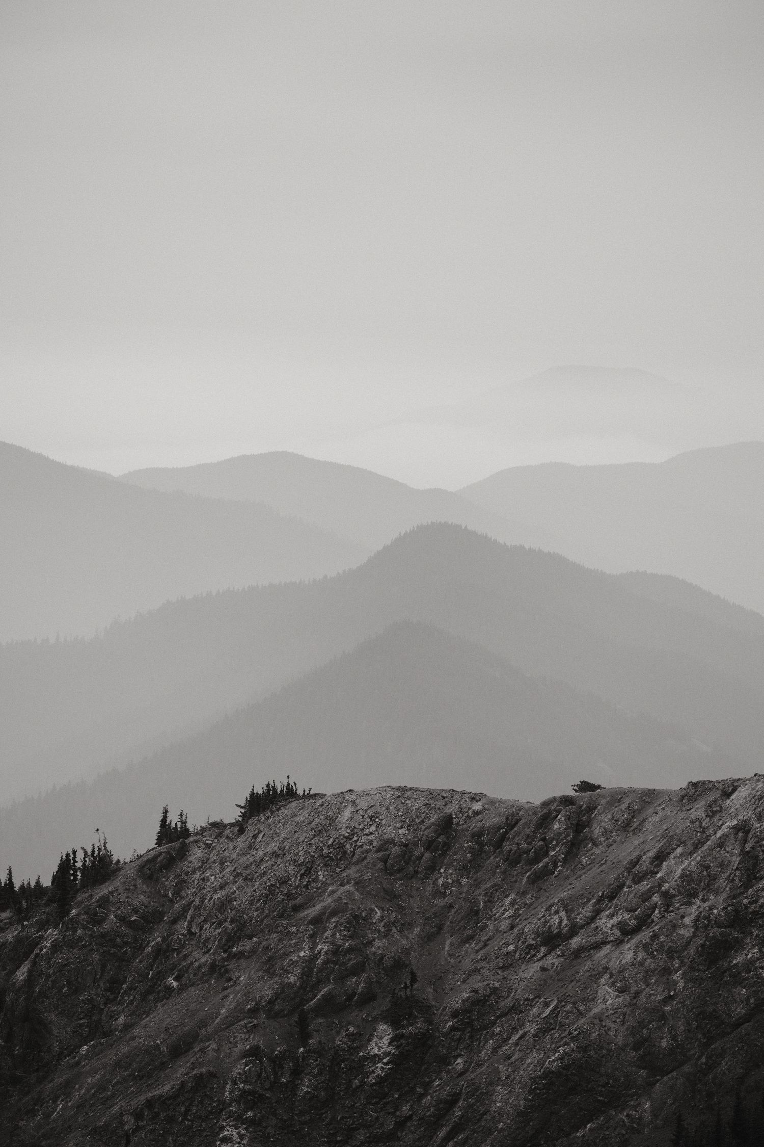 Misty mountain ridges fade into the distance in black and white.