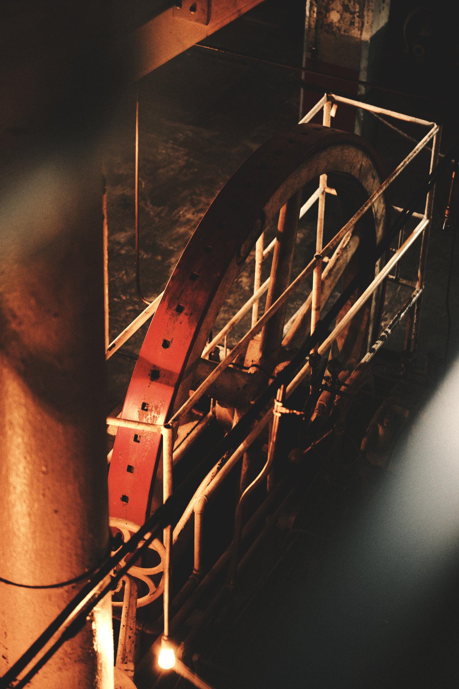 Industrial machinery parts illuminated in warm orange tones against dark background.