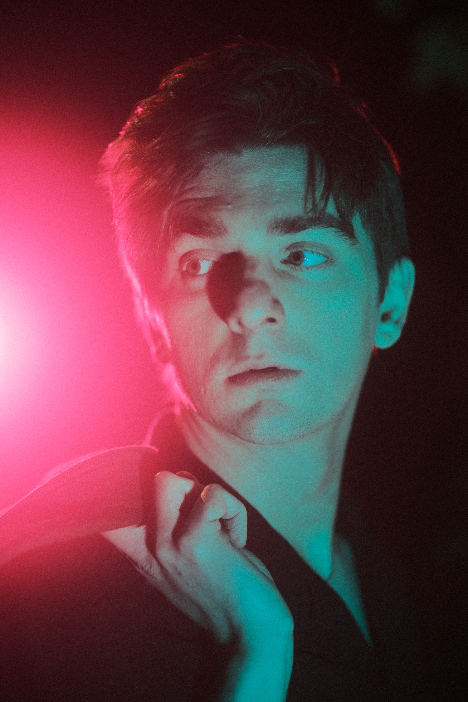 Dramatic portrait with neon red and blue lighting creating moody atmosphere.