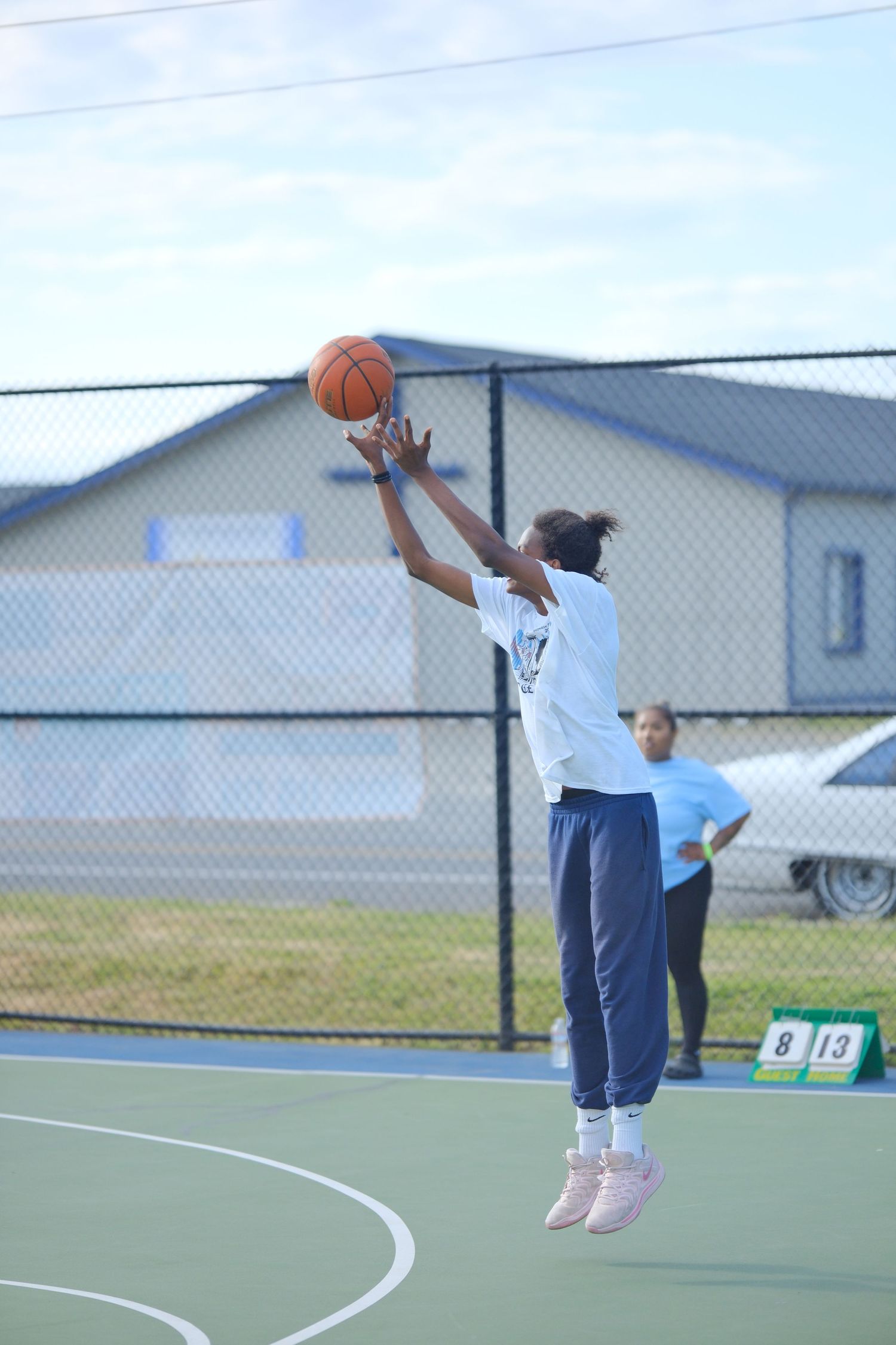 Basketball player jumping high to make a shot on outdoor court.