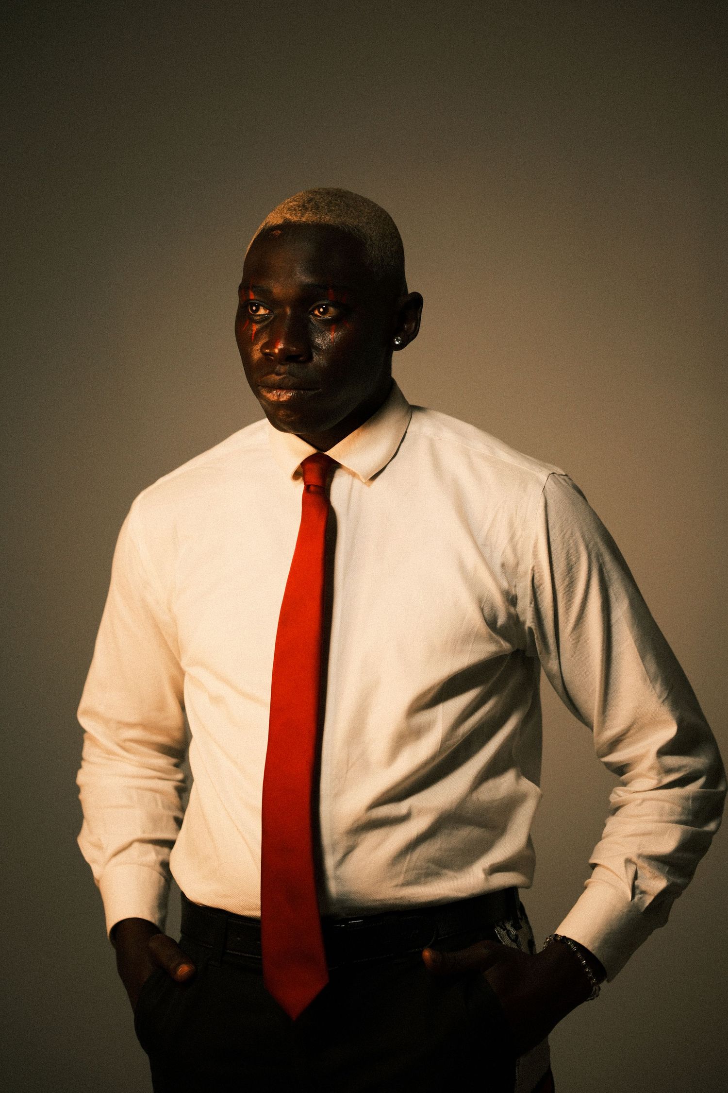 Professional portrait in white shirt and red tie against dark background.