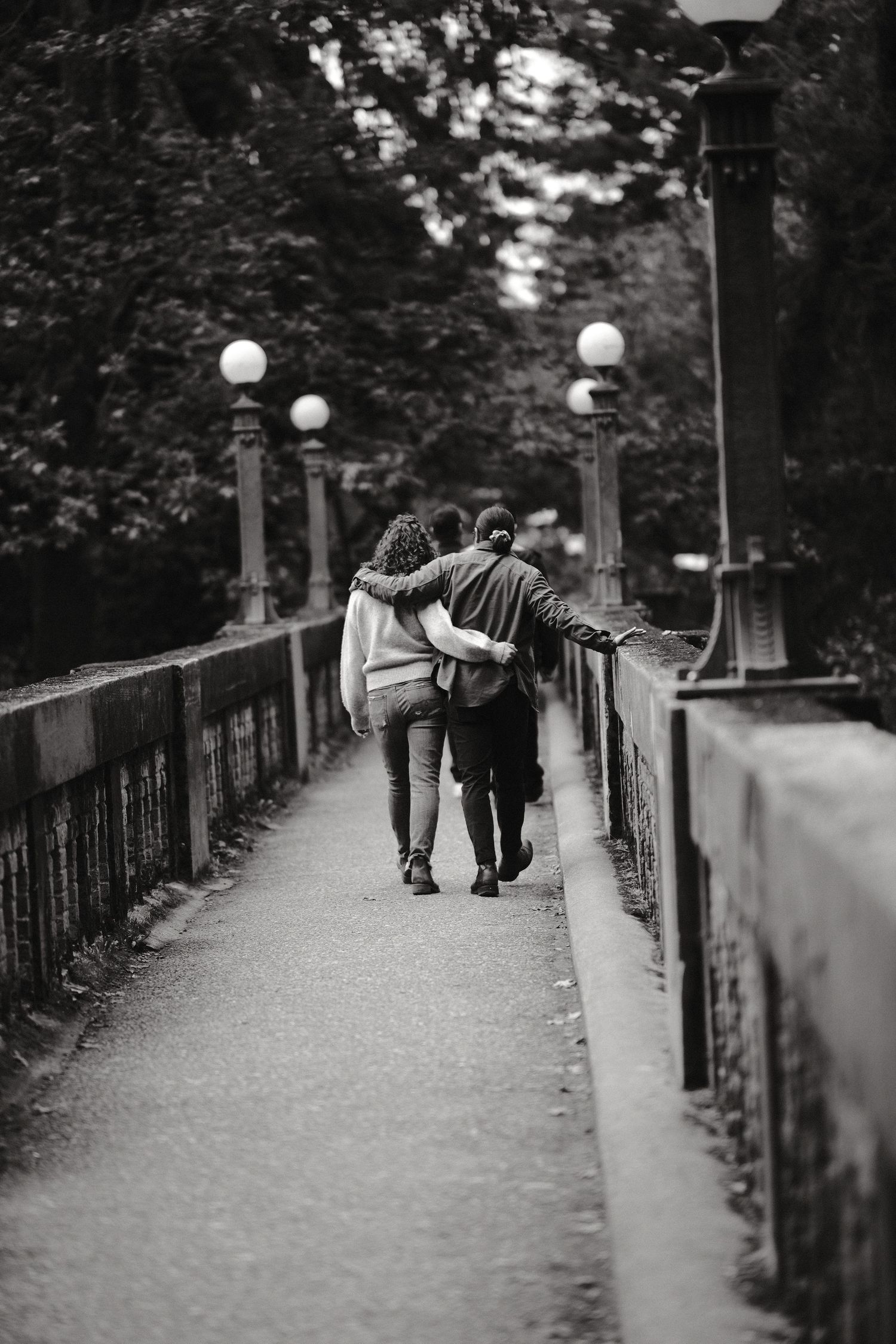 A black and white sequence of people walking together on a tree-lined pathway.