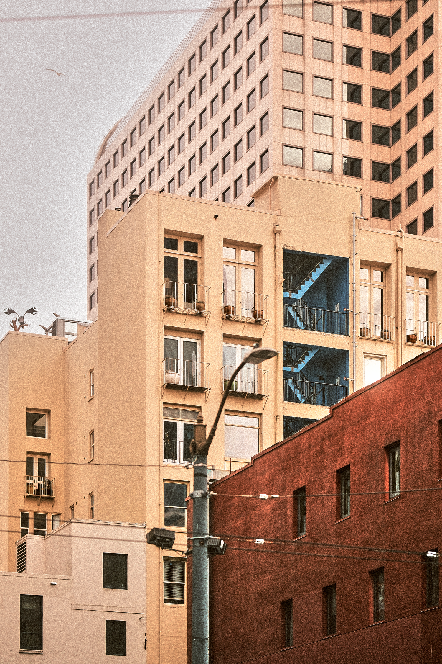 Modern beige office building with geometric windows and red brick lower section.