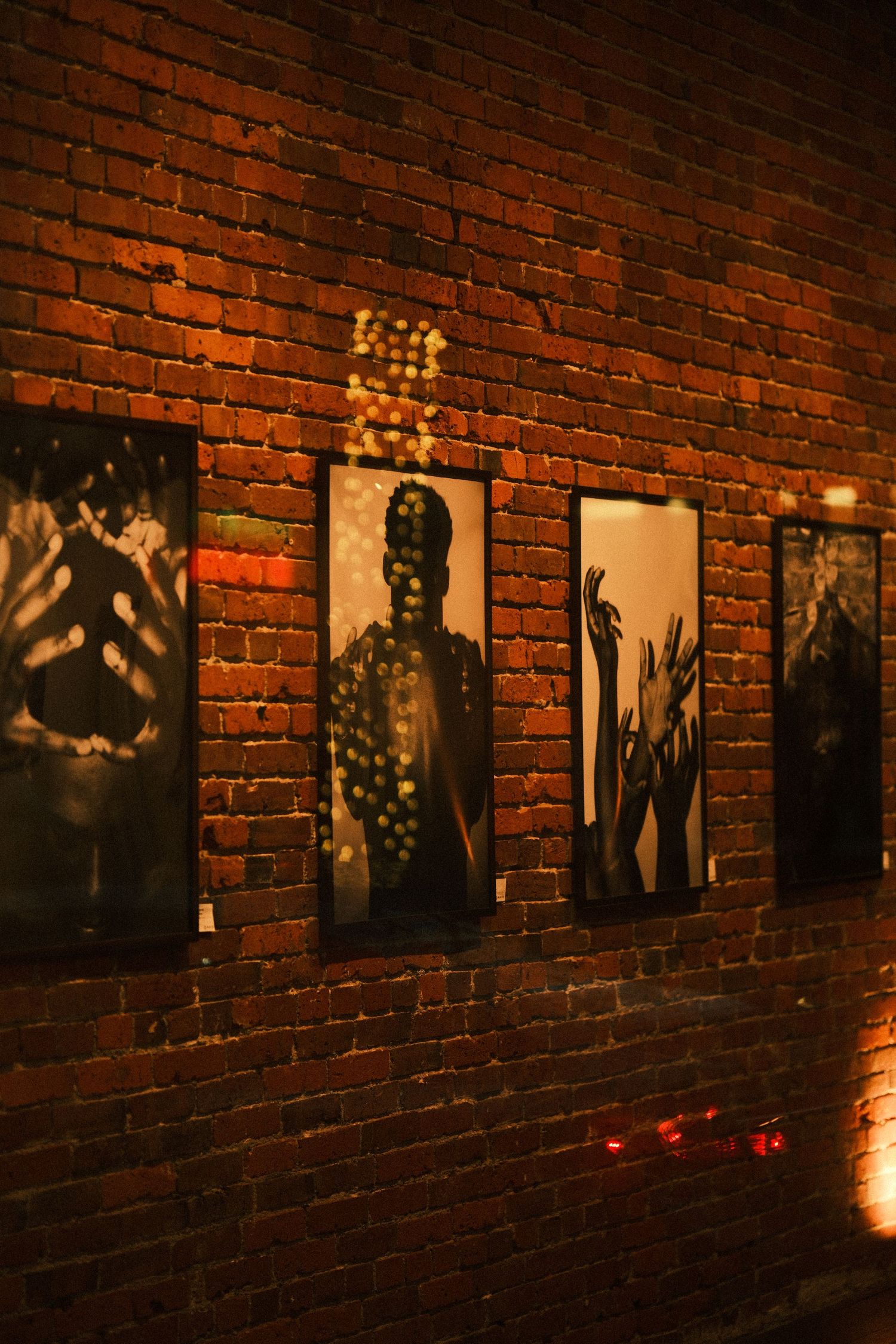 Artistic silhouette photographs displayed in a row on exposed brick wall with dramatic lighting.