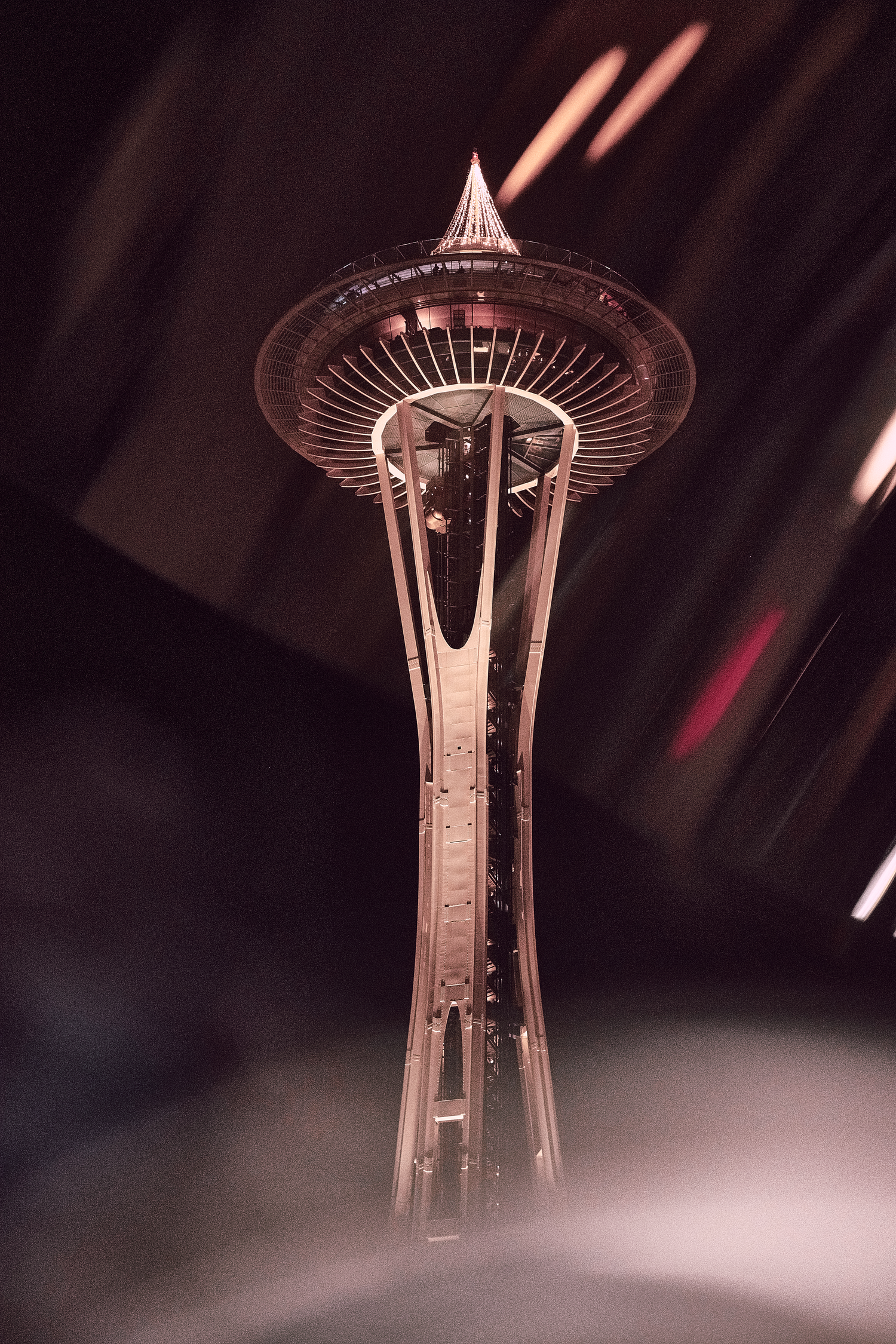 The Seattle Space Needle tower photographed at night with dramatic lighting.