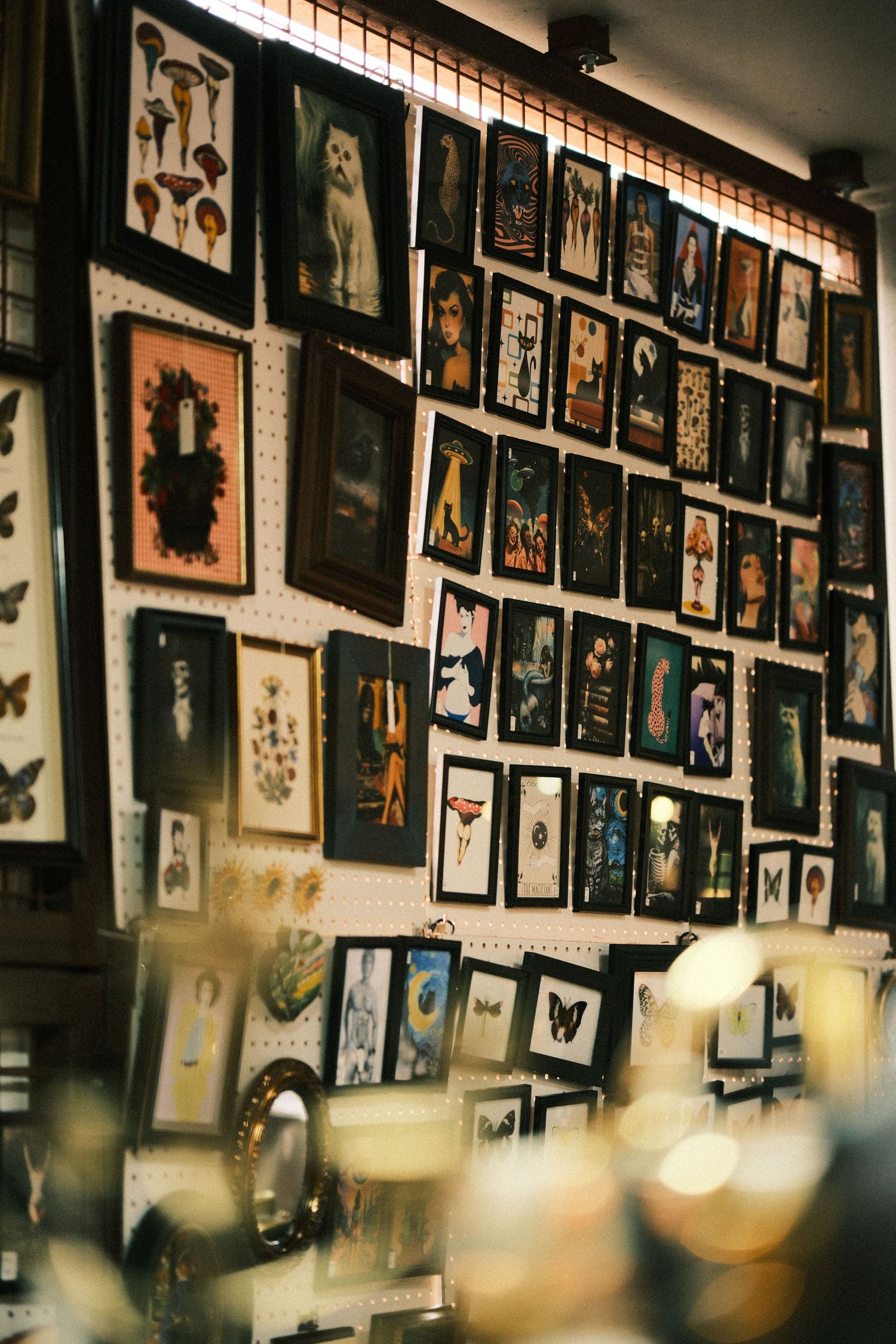 Vintage gallery wall with multiple framed photographs and artwork displayed under warm lighting.