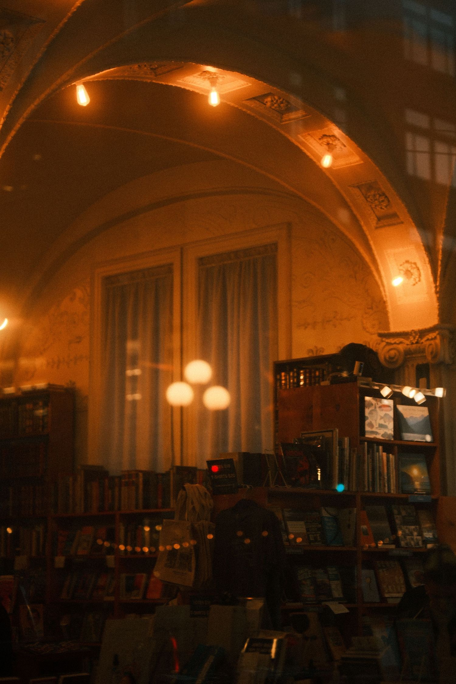 Arched interior space with string lights creating warm ambiance in historic building.