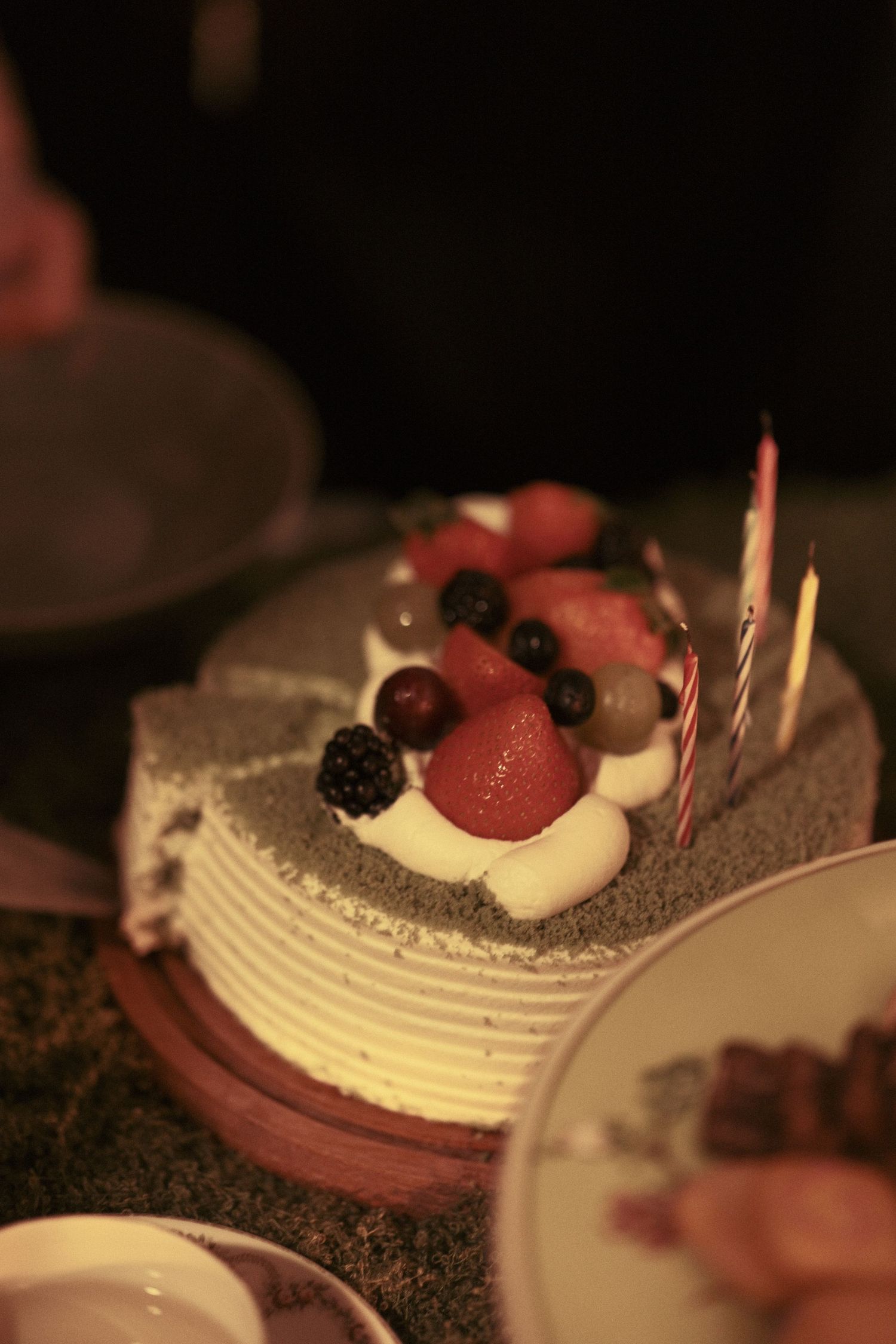 A beautifully plated dessert with fresh berries and cream on a dark background.