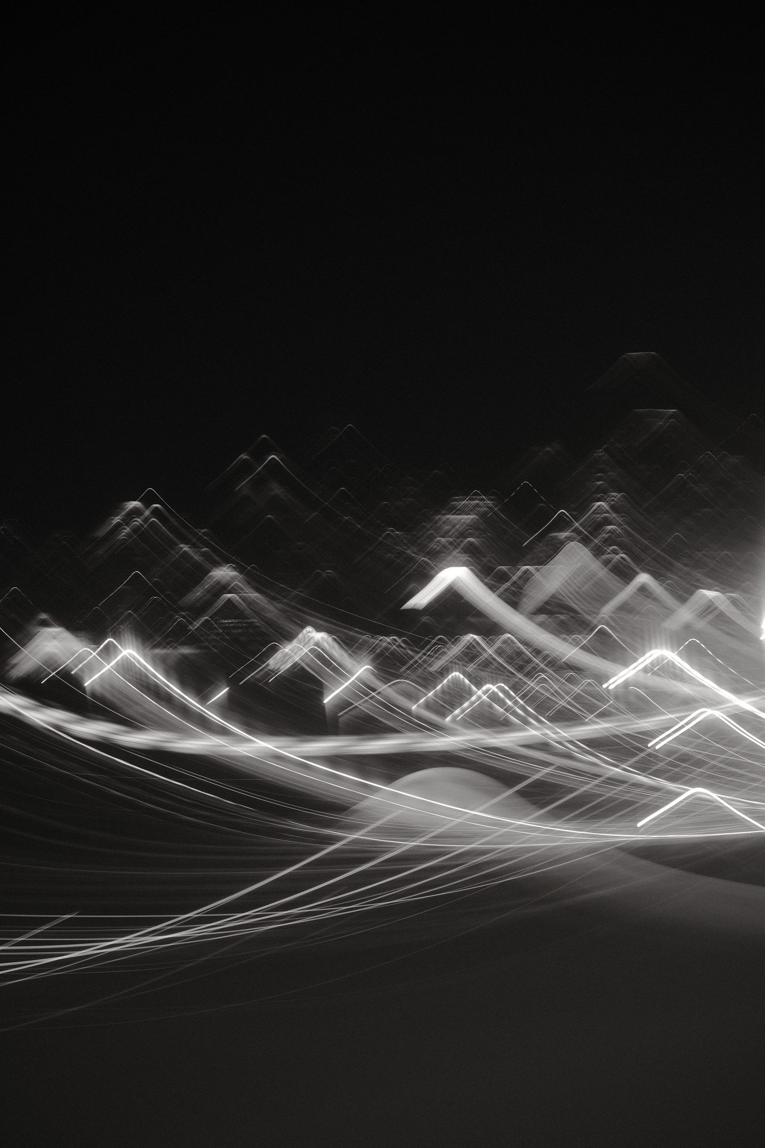 Abstract mountain-like shapes formed by white light streaks on dark background.